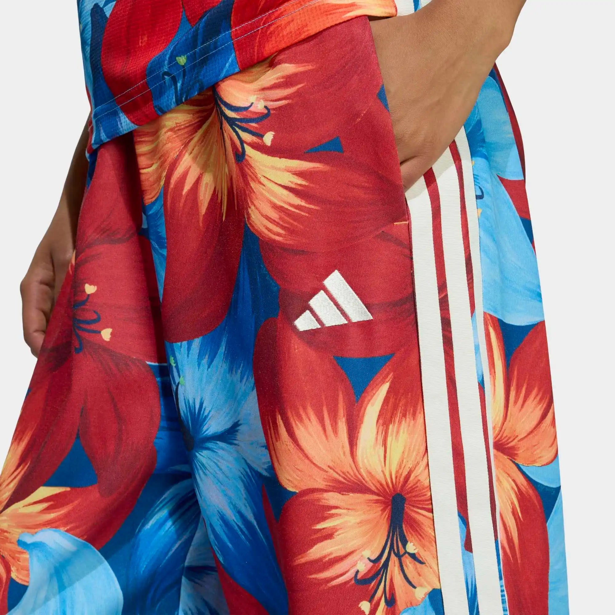 „Hellblaue und rot farbene adidas Originals x Farm Rio Tiro Trainingshose mit auffälligem tropischem Blumenmuster an den Seiten, klassischen weißen 3-Streifen und elastischem Bund bei Stickabush Berlin.“