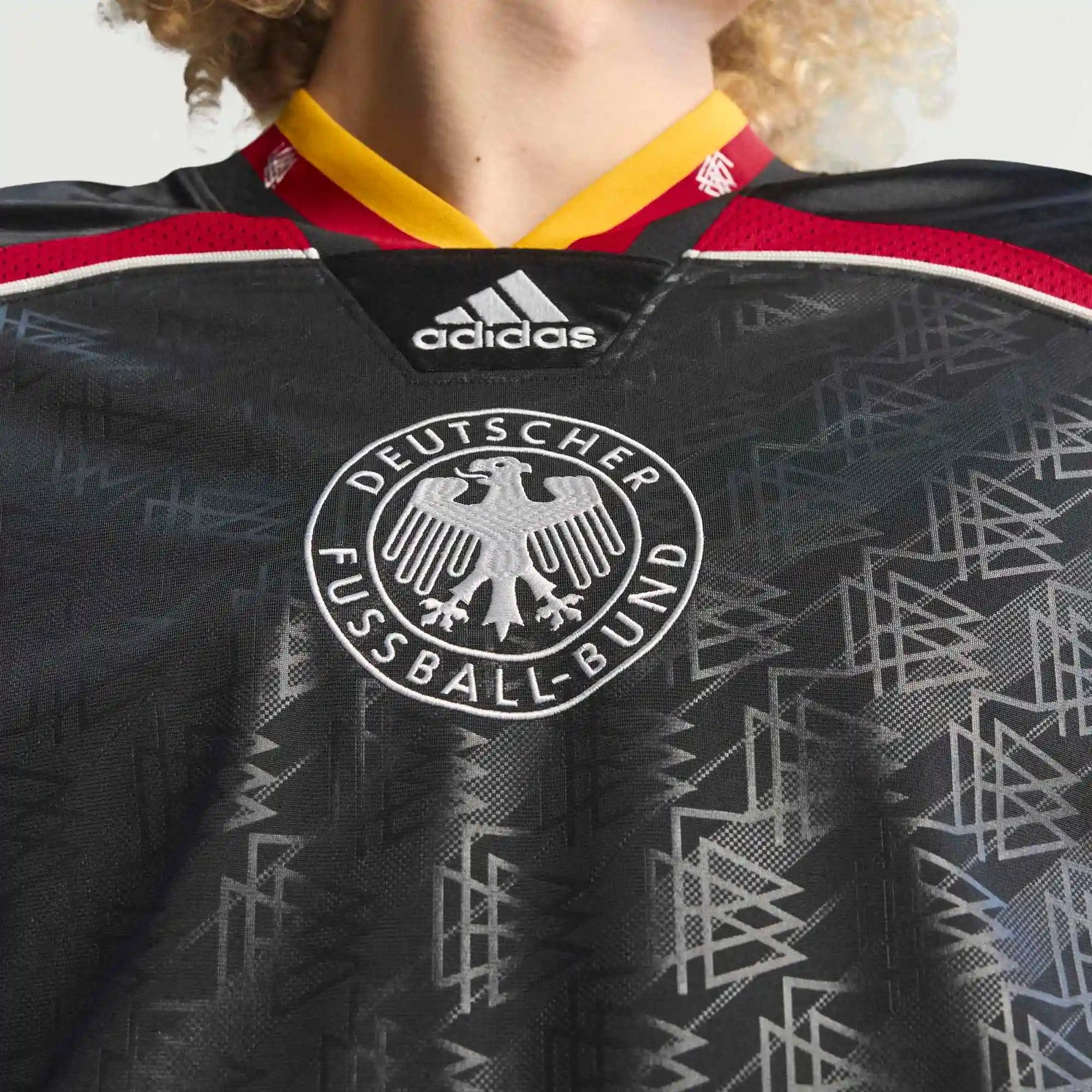 “Frontansicht Model Logo des adidas Originals Bringback Remixed DFB Trikots KD5980 in Schwarz mit der großen weißen Nummer 3 und kleinen Nummern an den Schultern bei Stickabush.“