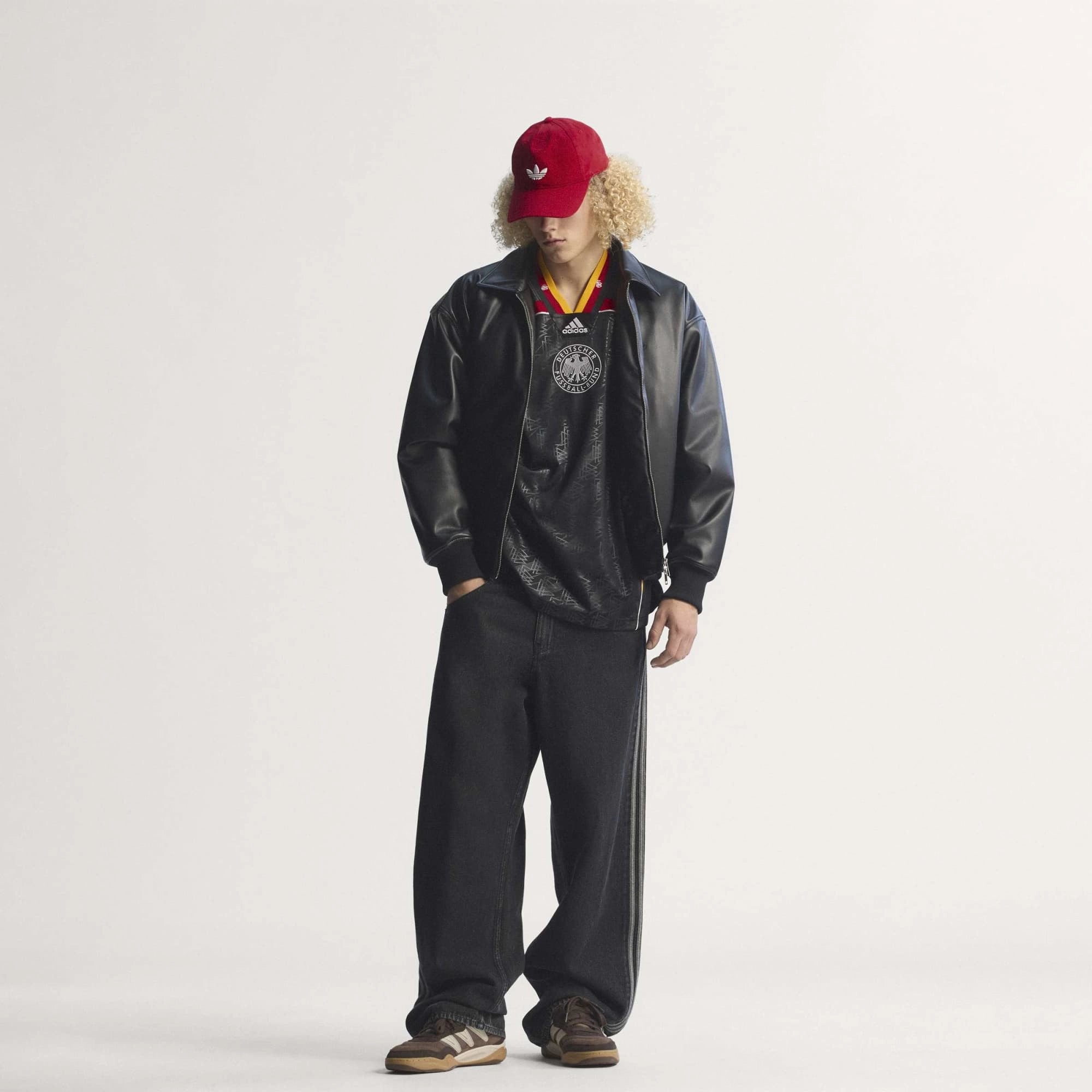 “Frontansicht Model Outfit mit Cap des adidas Originals Bringback Remixed DFB Trikots KD5980 in Schwarz mit der großen weißen Nummer 3 und kleinen Nummern an den Schultern bei Stickabush.“