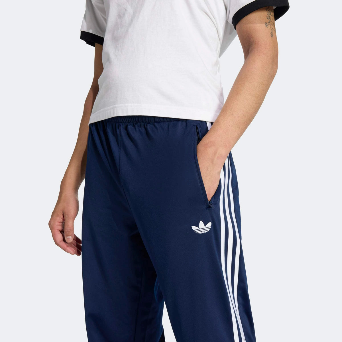 adidas Originals Firebird Track Pants in Night Indigo – Vorderansicht Details am Model der dunkelblauen Trainingshose im Retro-Look mit den ikonischen 3-Stripes.