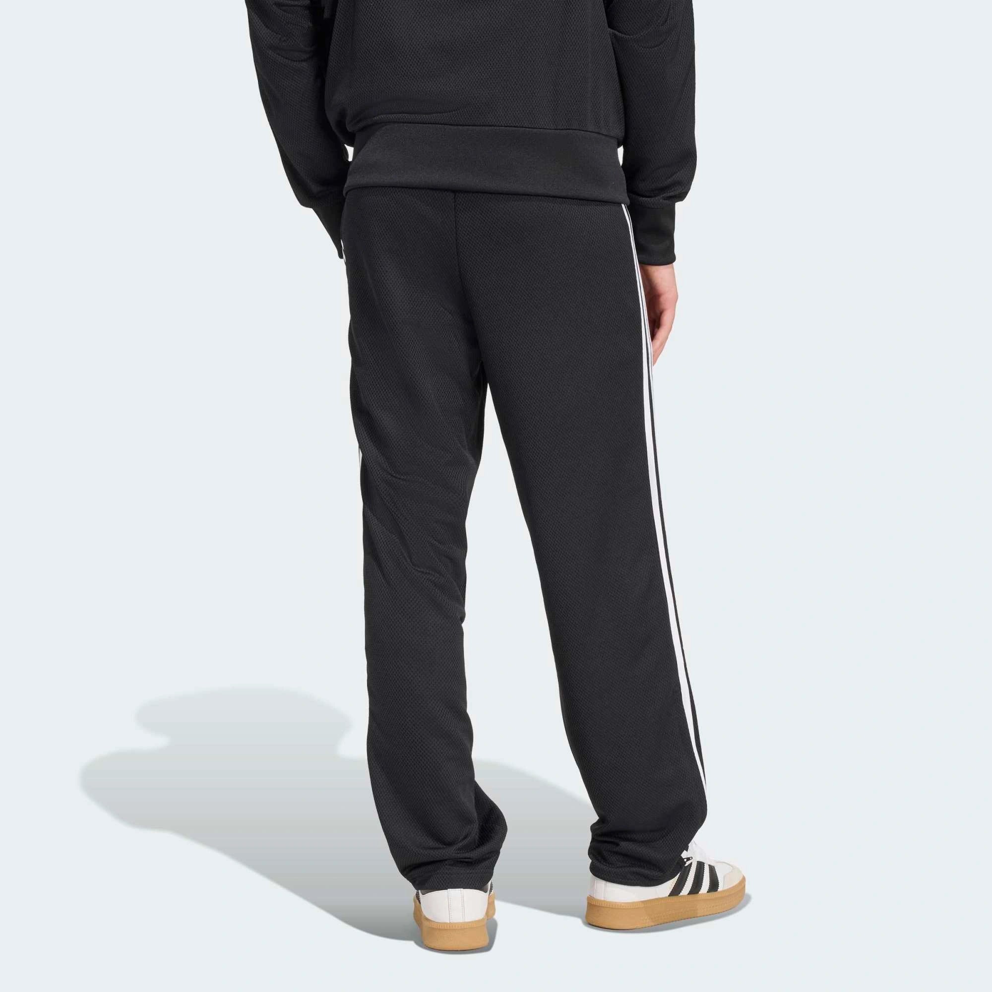 “Adidas Originals Firebird Track Pants Mesh in Schwarz mit weißen Streifen, Frontansicht des Trefoil-Logos und Mesh-Textur bei Stickabush Berlin.“