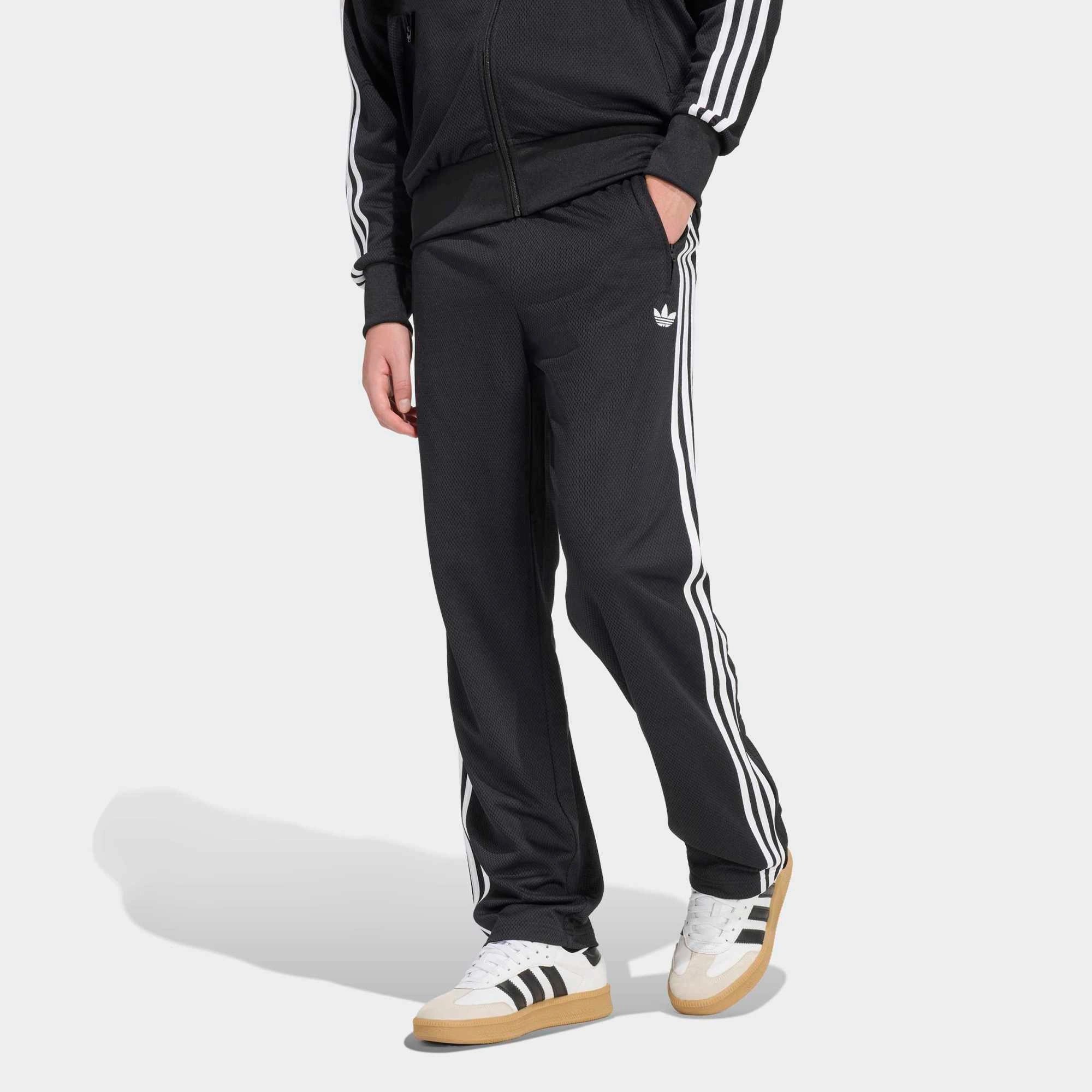“Adidas Originals Firebird Track Pants Mesh in Schwarz mit weißen Streifen, Frontansicht des Trefoil-Logos und Mesh-Textur bei Stickabush Berlin.“