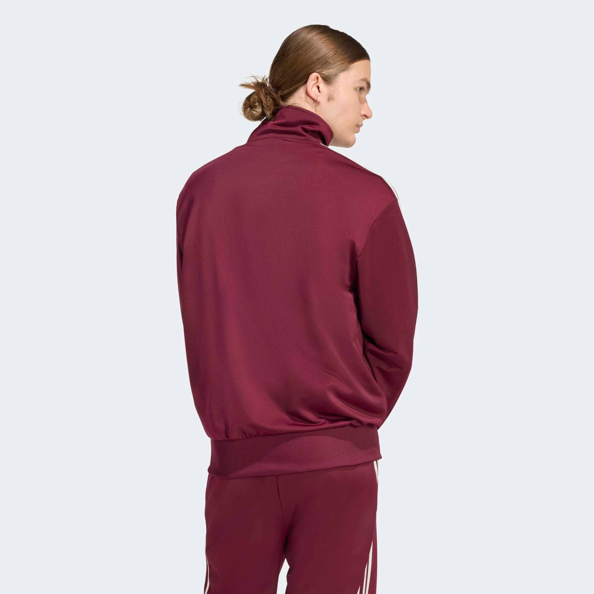 „Weinrote adidas Originals Firebird Trainingsjacke mit weißen 3-Streifen, Stehkragen und Trefoil-Logo in der Farbkombination Maroon / Off White bei Stickabush Berlin.“