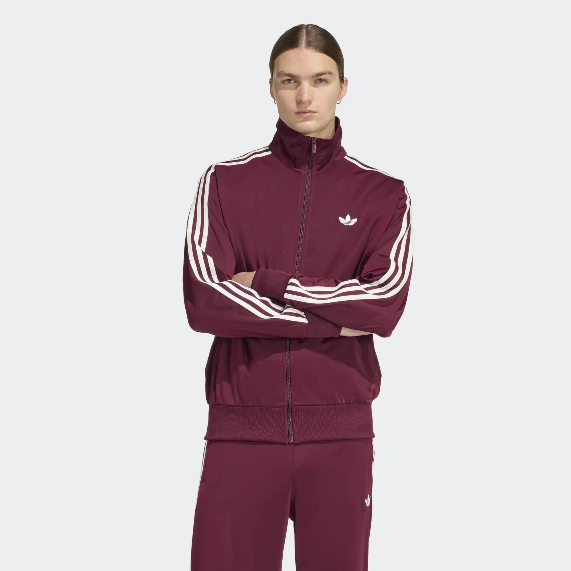 „Weinrote adidas Originals Firebird Trainingsjacke mit weißen 3-Streifen, Stehkragen und Trefoil-Logo in der Farbkombination Maroon / Off White bei Stickabush Berlin.“