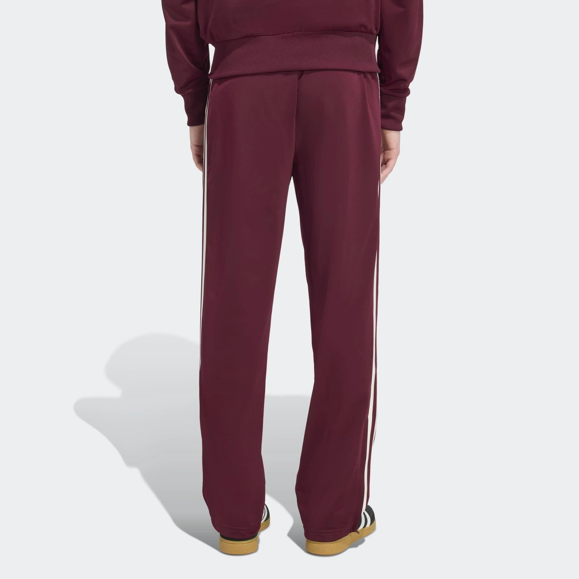 „Rückansicht Outfit Model der Adidas Originals Firebird Track Pants in Maroon (Dunkelrot) mit cremeweißen 3-Streifen – Klassische Retro-Trainingshose bei Stickabush Berlin.“