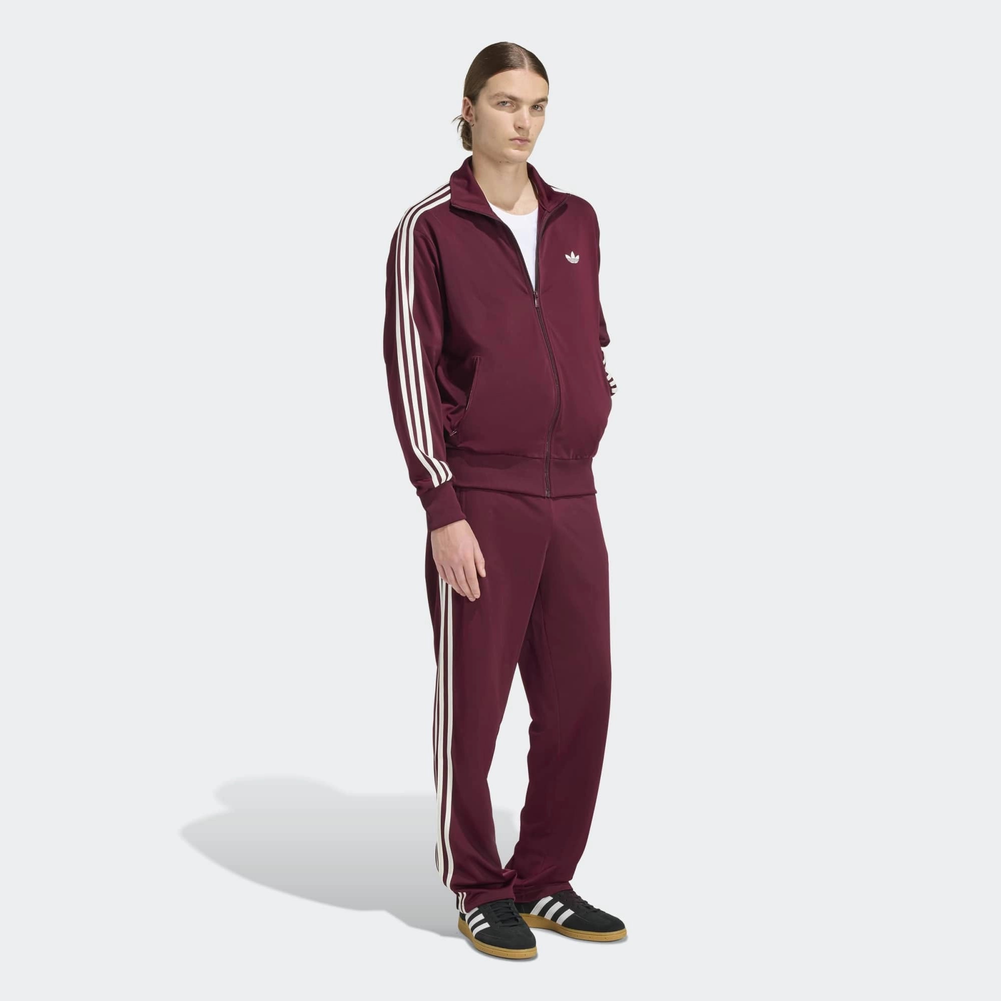 „Frontansicht Outfit Model der Adidas Originals Firebird Track Pants in Maroon (Dunkelrot) mit cremeweißen 3-Streifen – Klassische Retro-Trainingshose bei Stickabush Berlin.“
