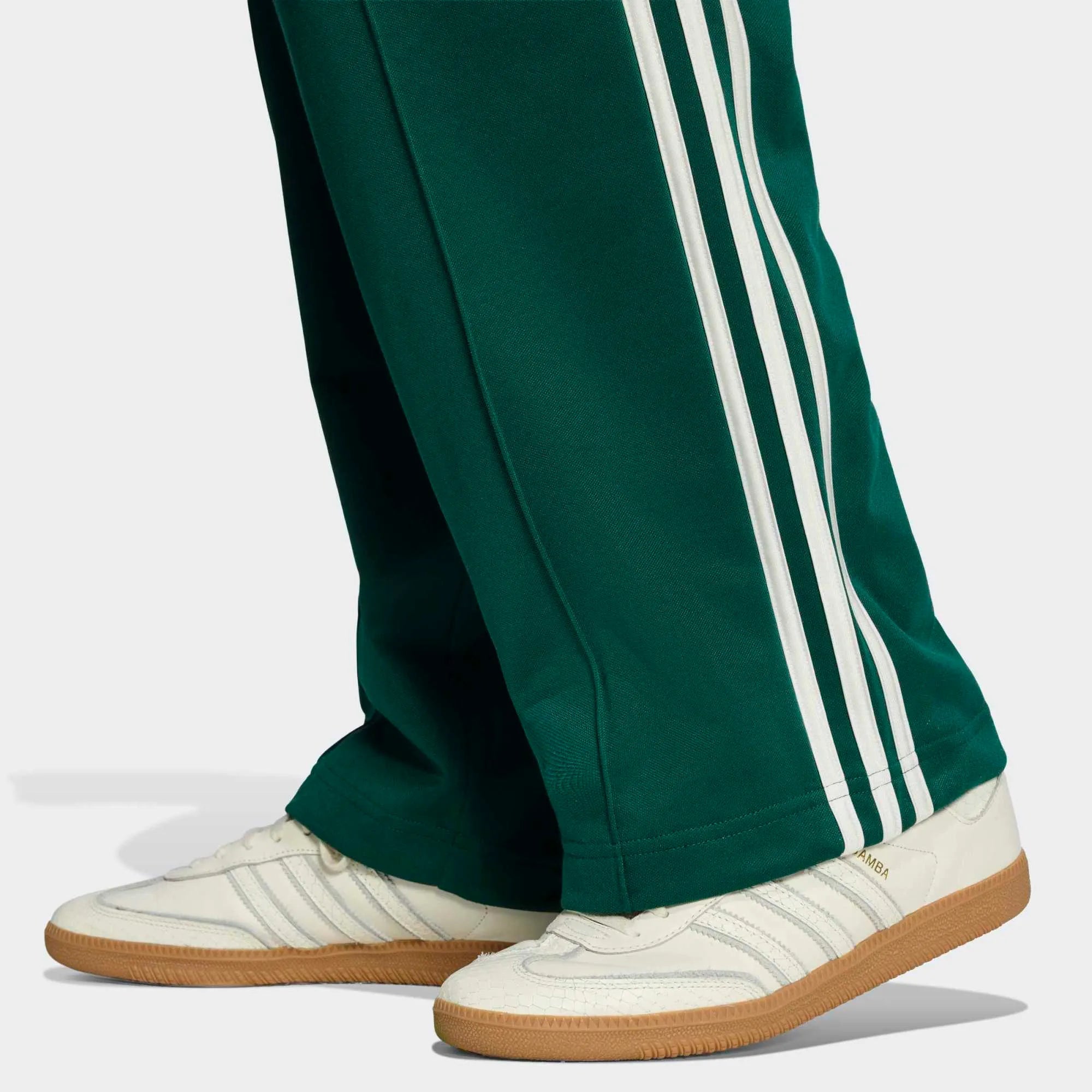 “Detailansicht Hosenbein der adidas Originals Baggy Track Pants in Collegiate Green mit weißen 3-Streifen, seitlichen Reißverschlusstaschen und weitem Beinabschluss bei Stickabush.“