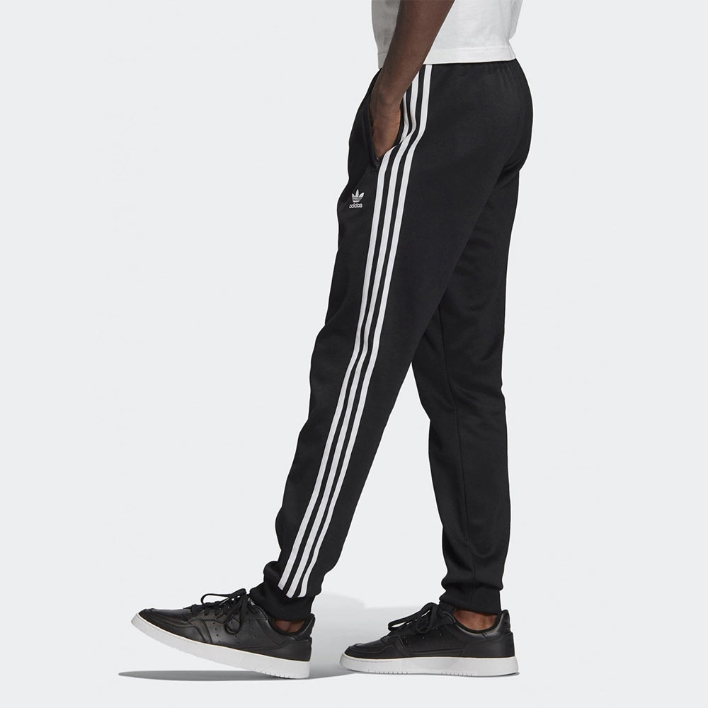 "Schwarze adidas Classics SST Trainingshose mit weißen 3-Streifen, Trefoil-Logo und schmal zulaufendem Bein bei Stickabush Berlin."