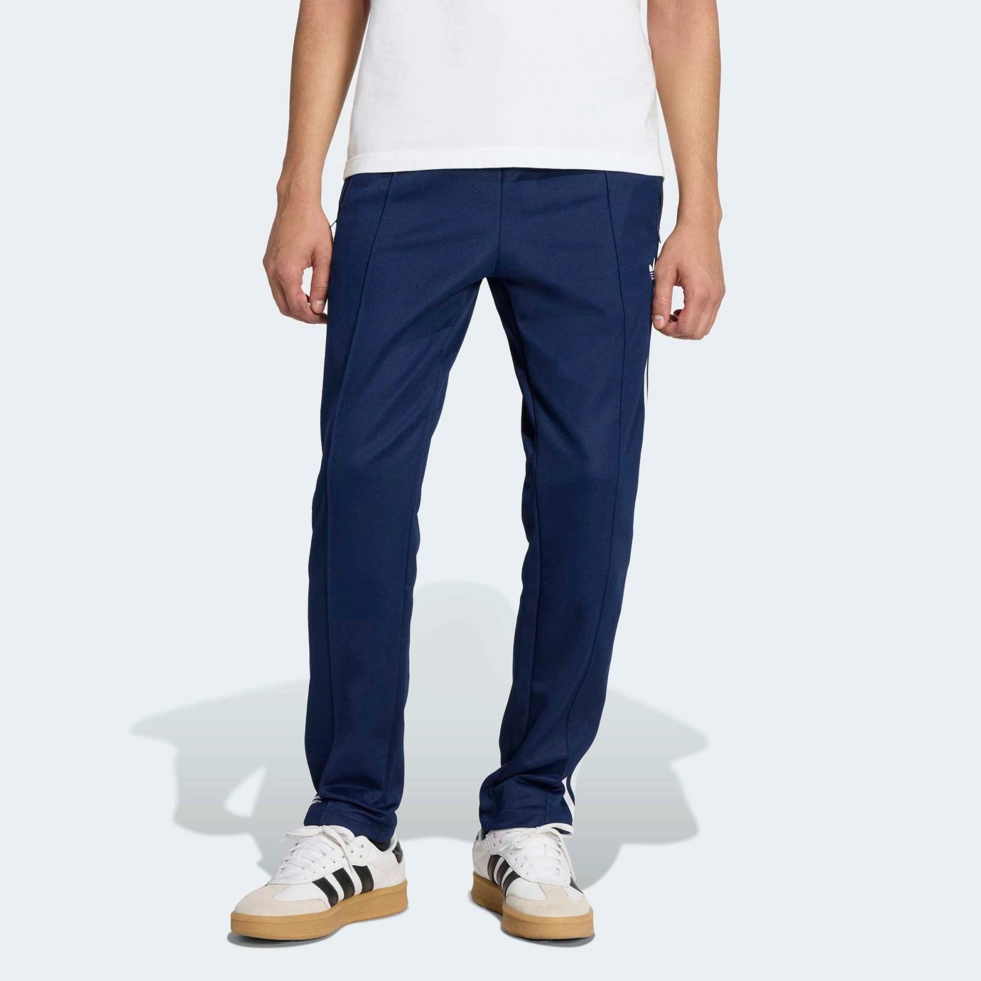 „Dunkelblaue Adidas Originals Beckenbauer Track Pant (Night Indigo) mit weißen 3-Streifen und klassischer Bügelfalte bei Stickabush Berlin.“