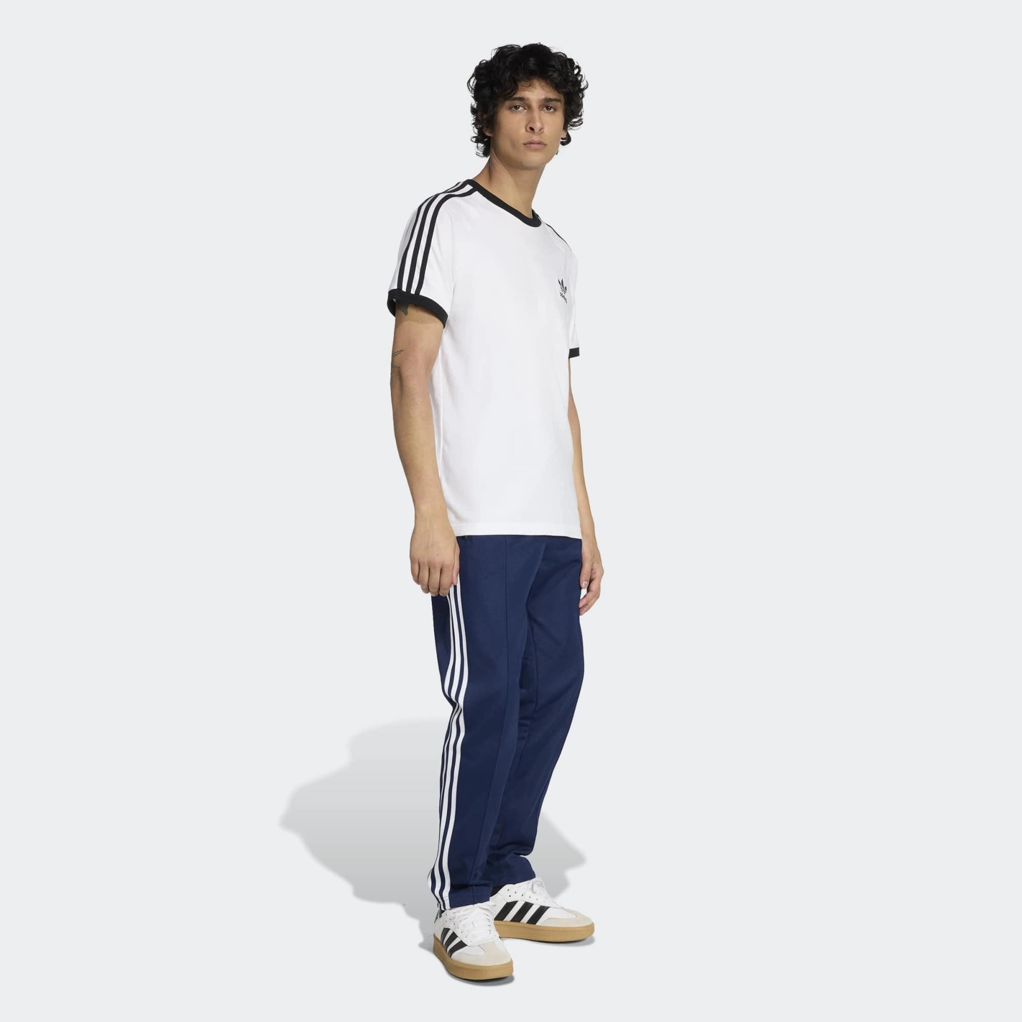 „Dunkelblaue Adidas Originals Beckenbauer Track Pant (Night Indigo) mit weißen 3-Streifen und klassischer Bügelfalte bei Stickabush Berlin.“