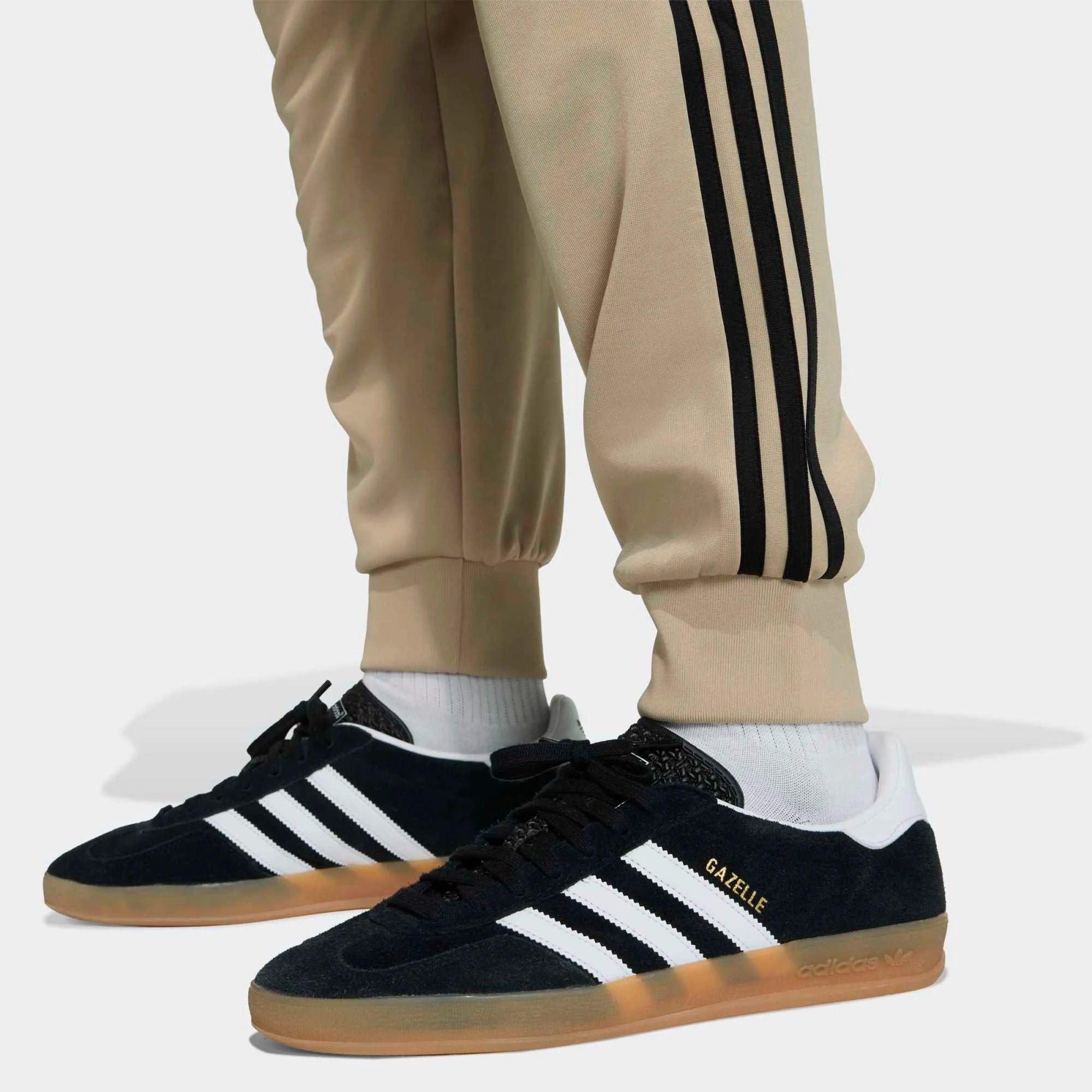 „Khakifarbene adidas Originals Classics SST Track Pants Trainingshose mit schwarzen 3-Streifen, gesticktem Trefoil-Logo und geradem Beinschnitt bei Stickabush Berlin.“