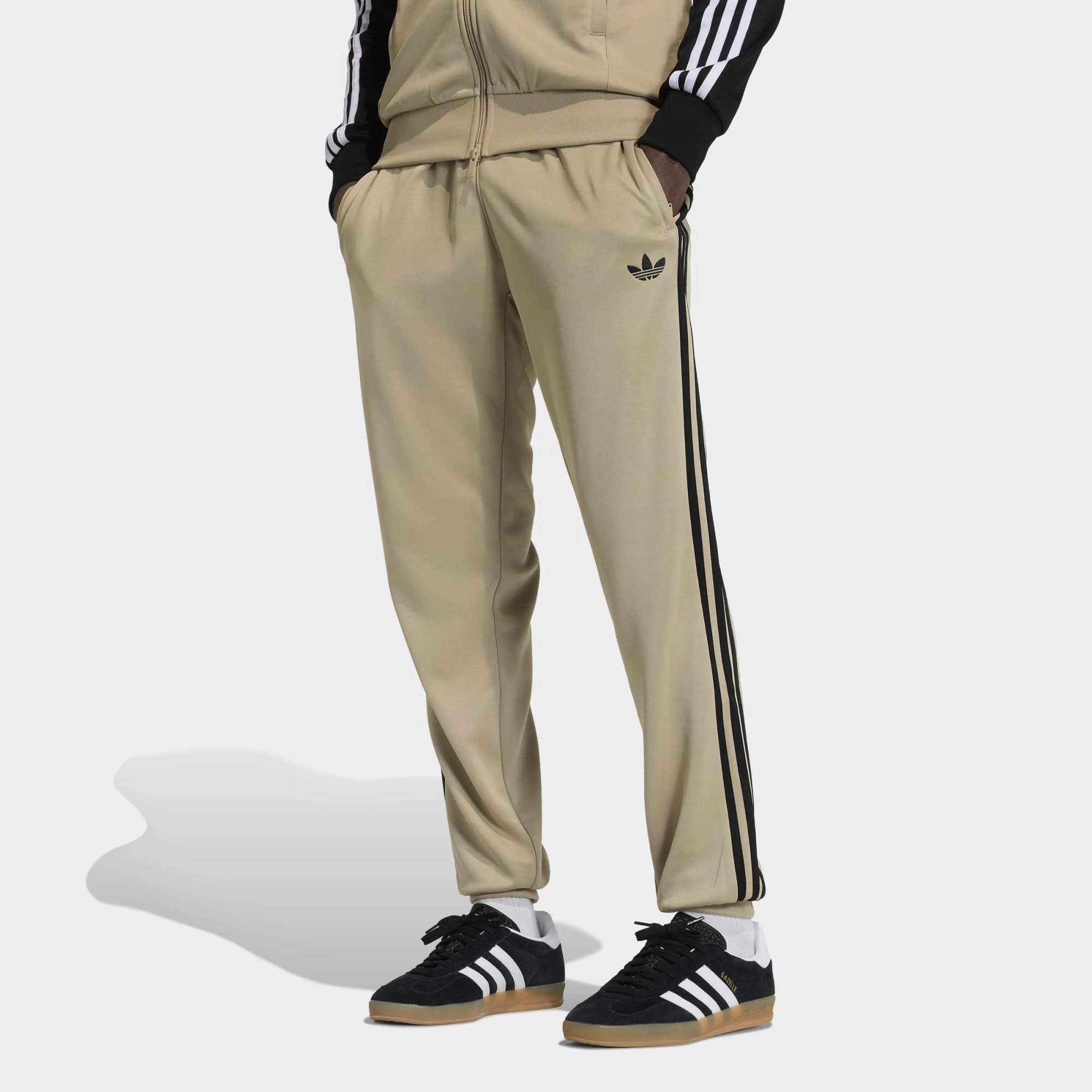 „Khakifarbene adidas Originals Classics SST Track Pants Trainingshose mit schwarzen 3-Streifen, gesticktem Trefoil-Logo und geradem Beinschnitt bei Stickabush Berlin.“