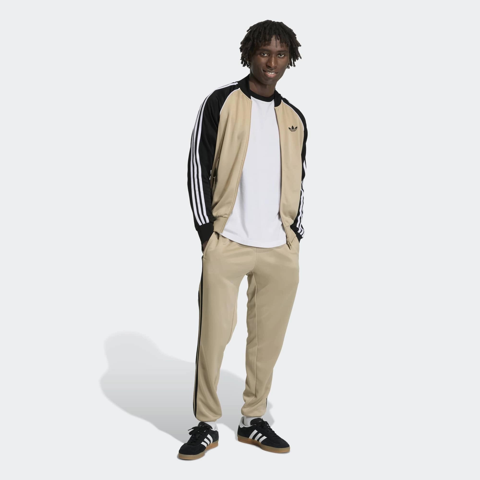 „Khakifarbene adidas Originals Firebird Trainingshose mit schwarzen 3-Streifen, gesticktem Trefoil-Logo und geradem Beinschnitt bei Stickabush Berlin.“