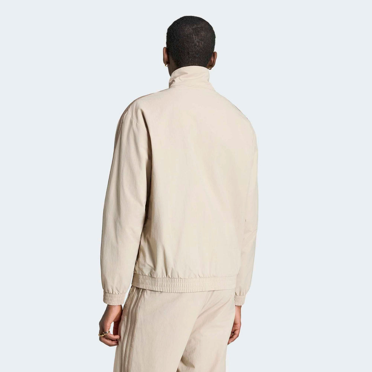 adidas Originals Firebird Woven Track Top in Beige am Model von hinten, hochauflösend präsentiert im STICKABUSH Store Berlin.