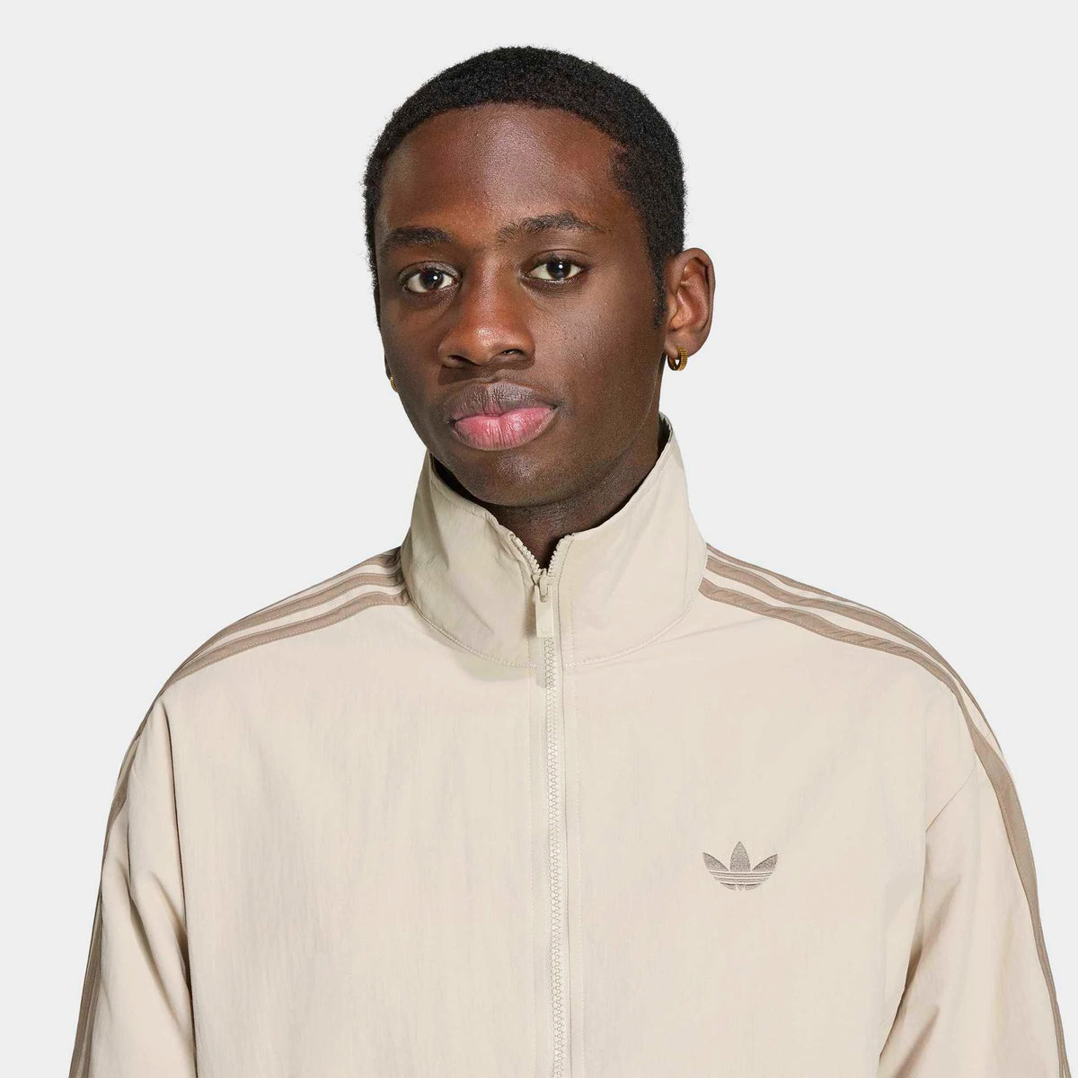 adidas Originals Firebird Woven Track Top in Beige Details am Model von vorne, hochauflösend präsentiert im STICKABUSH Store Berlin.