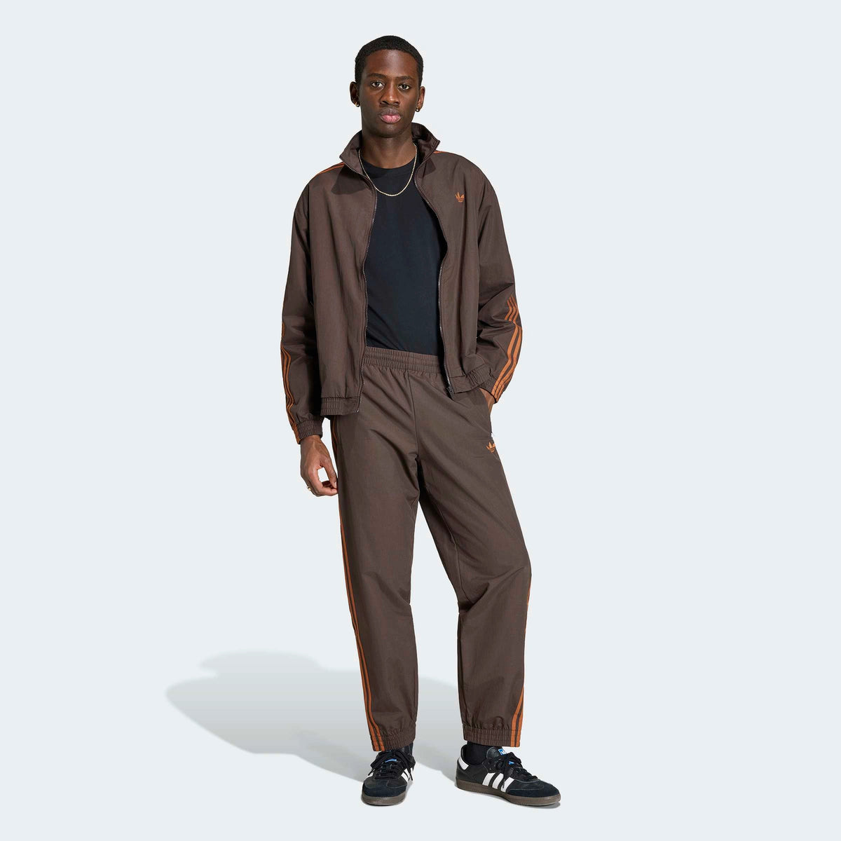 adidas Originals Firebird Woven Track Pants in Aurora Coffee – Vorderansicht Outfit am Model der braunen Trainingshose aus Webmaterial mit den ikonischen 3-Stripes.