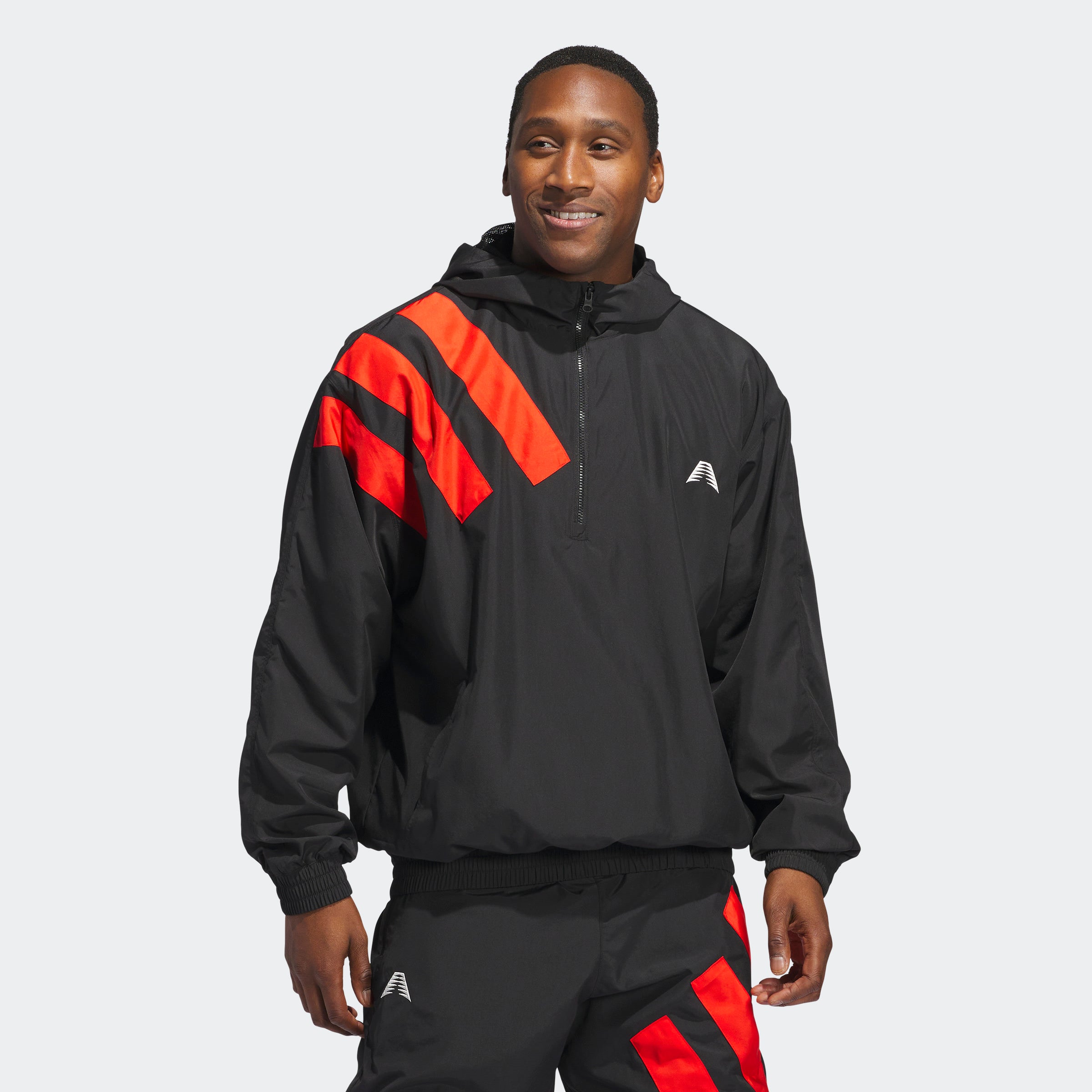 “Der Adidas Anthony Edwards Anorak Pullover in Schwarz, JC8782, verfügt über eine Kapuze mit drei auffälligen roten Diagonalstreifen auf der linken oberen Schulter, hlaben Reißverschluss und aus Polyester gefertigt.“