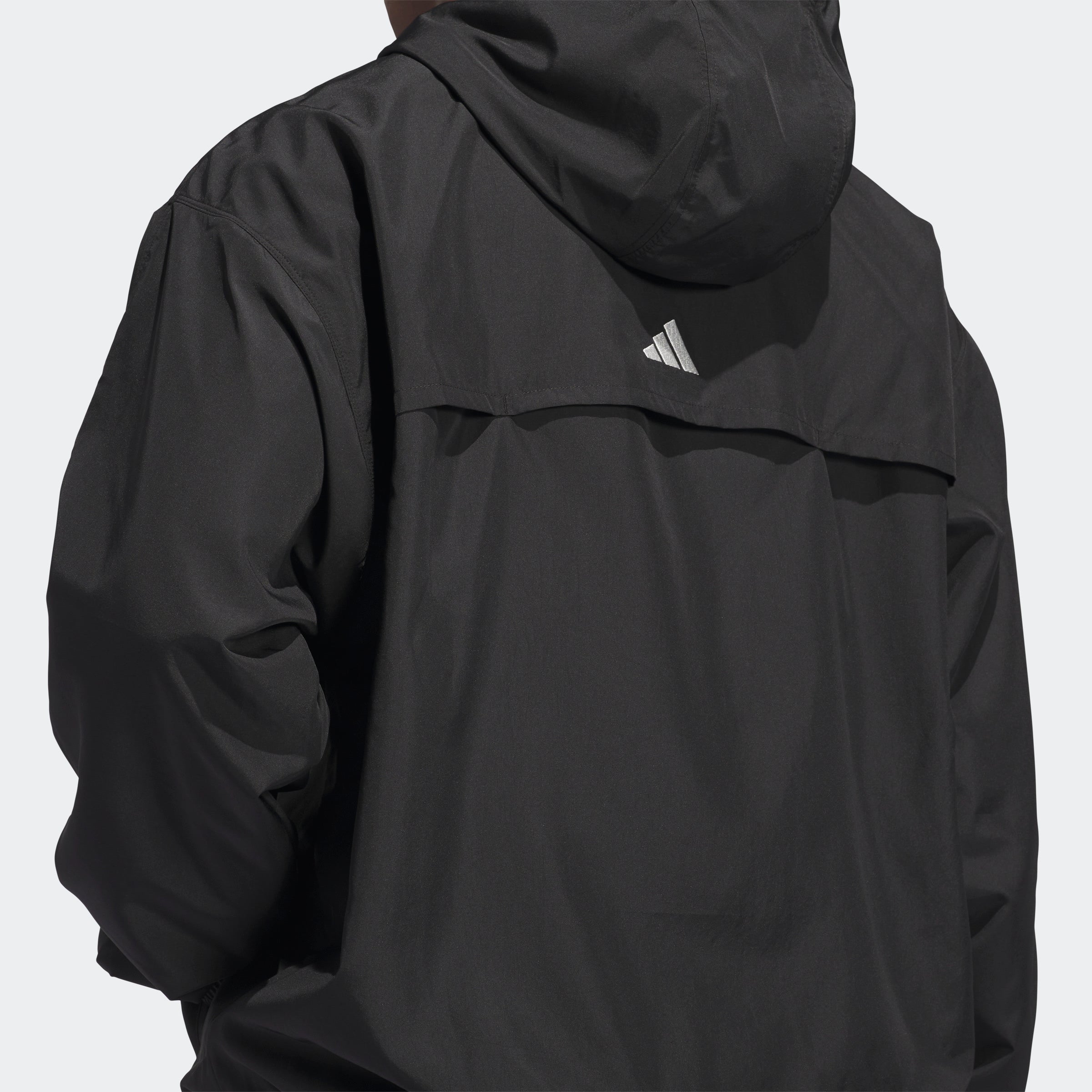 “The Adidas Originals Anthony Edwards Anorak Pullover in black, JC8782, features a hooded design with three bold red diagonal stripes on the upper left shoulder. Made from recycled materials, this durable nylon pullover includes a halfway zipper, white chest logo, and elastic cuffs and waistband for a snug fit.“
