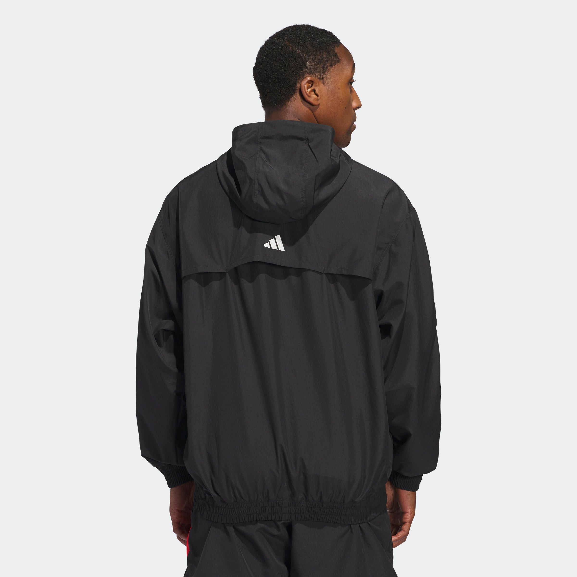 “Der Adidas Anthony Edwards Anorak Pullover in Schwarz, JC8782, verfügt über eine Kapuze mit drei auffälligen roten Diagonalstreifen auf der linken oberen Schulter, hlaben Reißverschluss und aus Polyester gefertigt.“