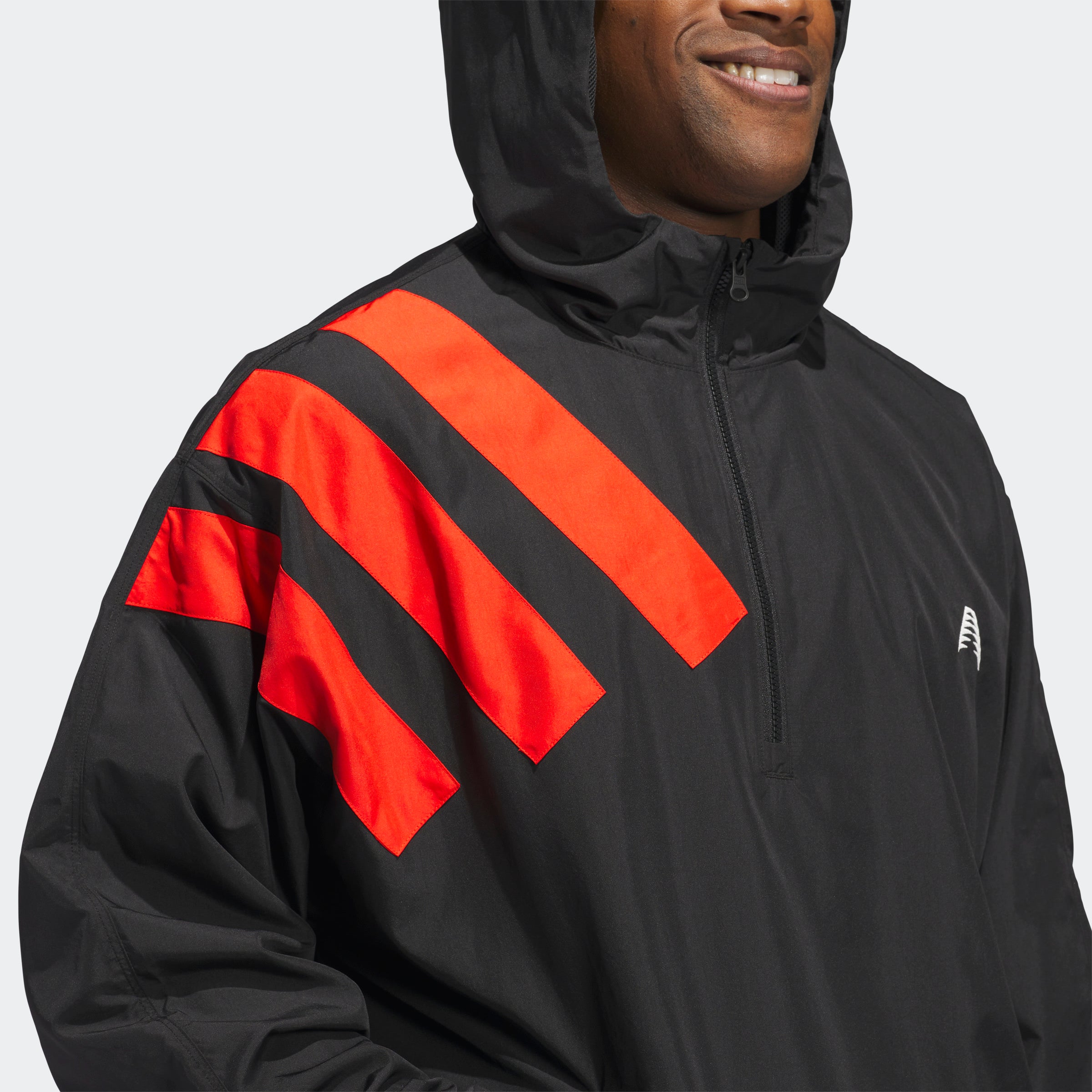 “Der Adidas Anthony Edwards Anorak Pullover in Schwarz, JC8782, verfügt über eine Kapuze mit drei auffälligen roten Diagonalstreifen auf der linken oberen Schulter, hlaben Reißverschluss und aus Polyester gefertigt.“