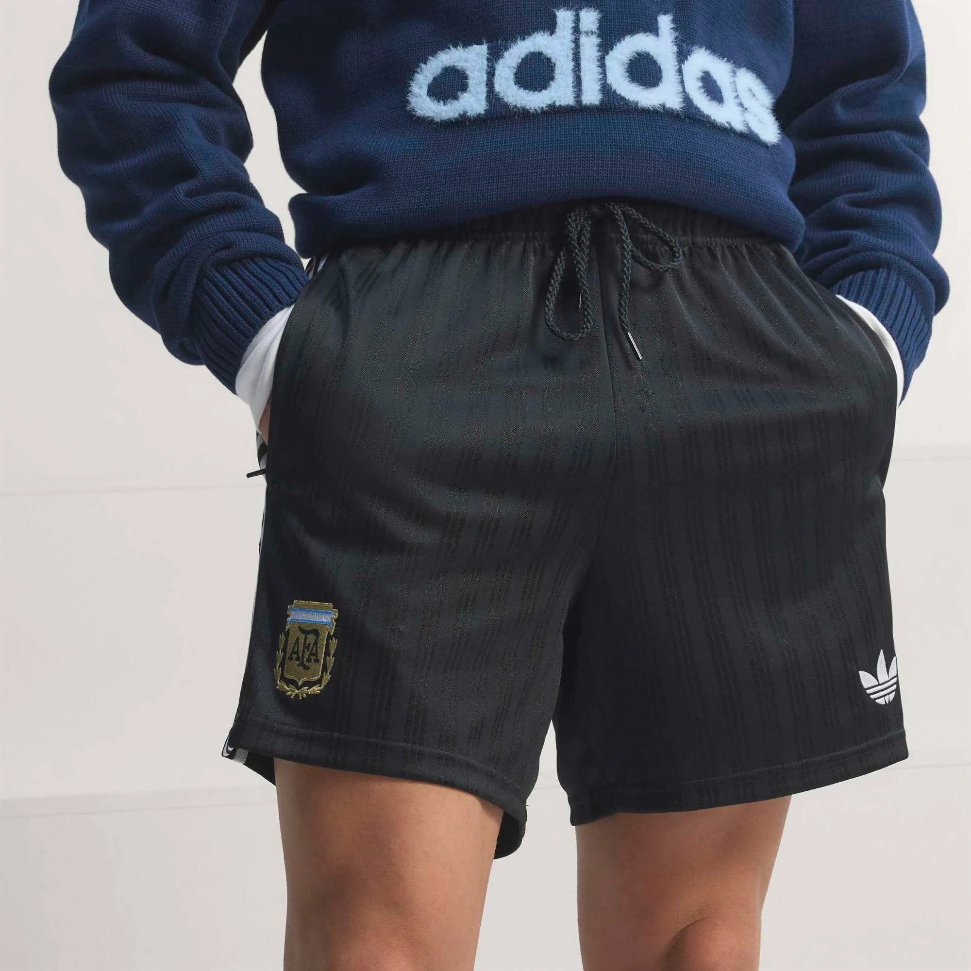 “Schwarze adidas Originals Argentinien OG Shorts mit weißen Streifen und gesticktem AFA-Verbandswappen bei Stickabush.“