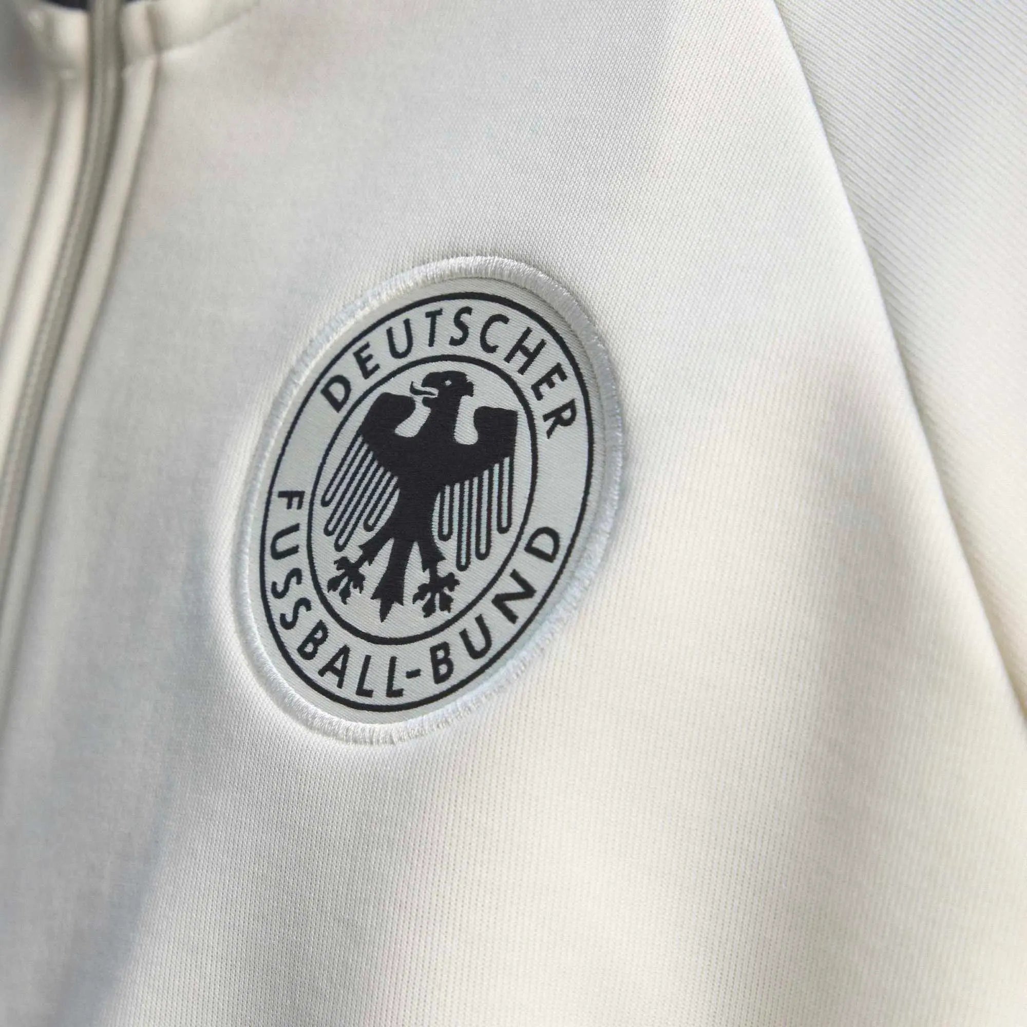 “Cremeweiße adidas Originals DFB Deutschland OG Trainingsjacke mit schwarzen Streifen und gesticktem DFB-Logo bei Stickabush.“