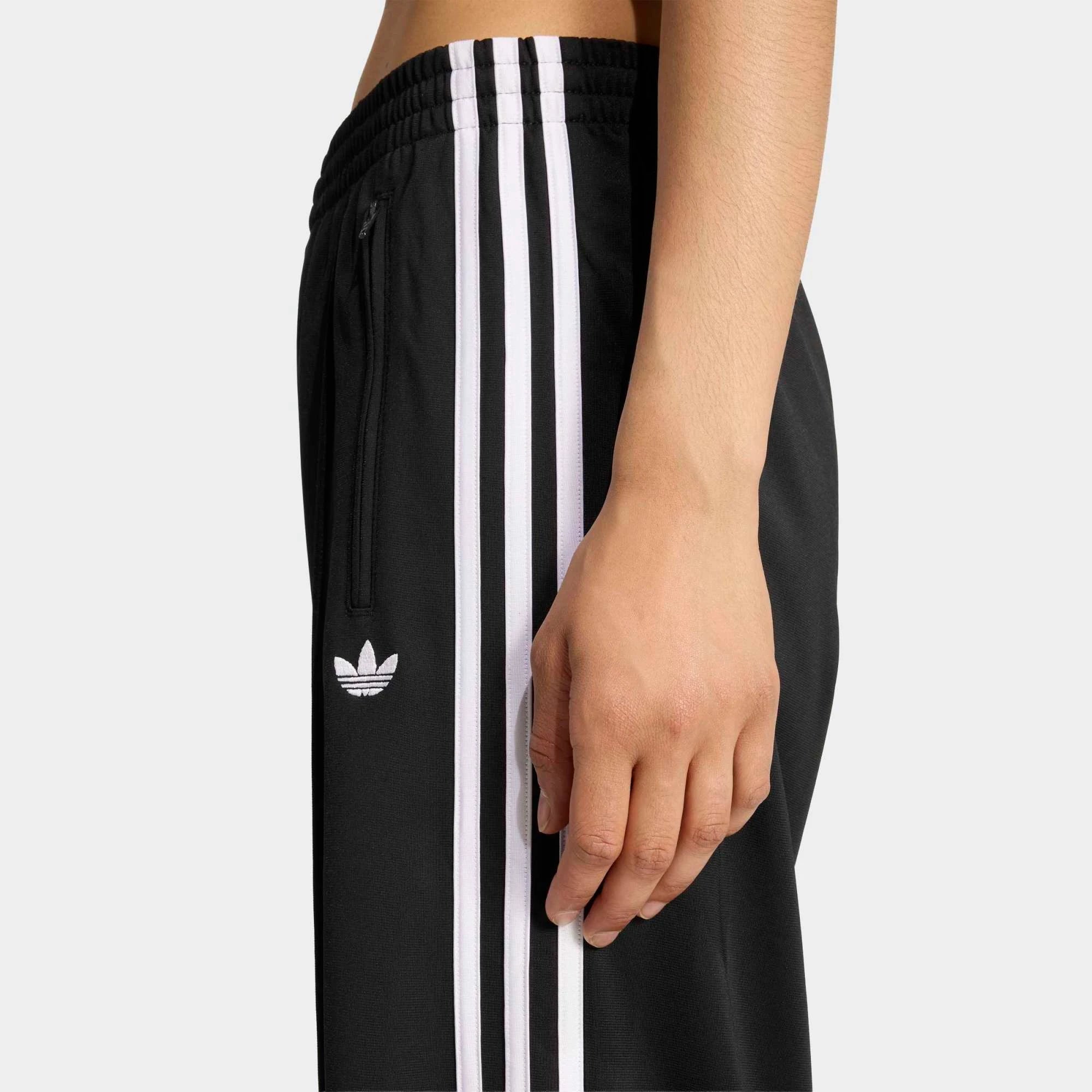 „Schwarze adidas Originals Firebird Loose Track Pants für Damen mit weißen 3-Streifen (Style-ID: KD7976) – weit geschnittene Streetwear-Trainingshose aus Trikot-Stoff bei Stickabush Berlin.“