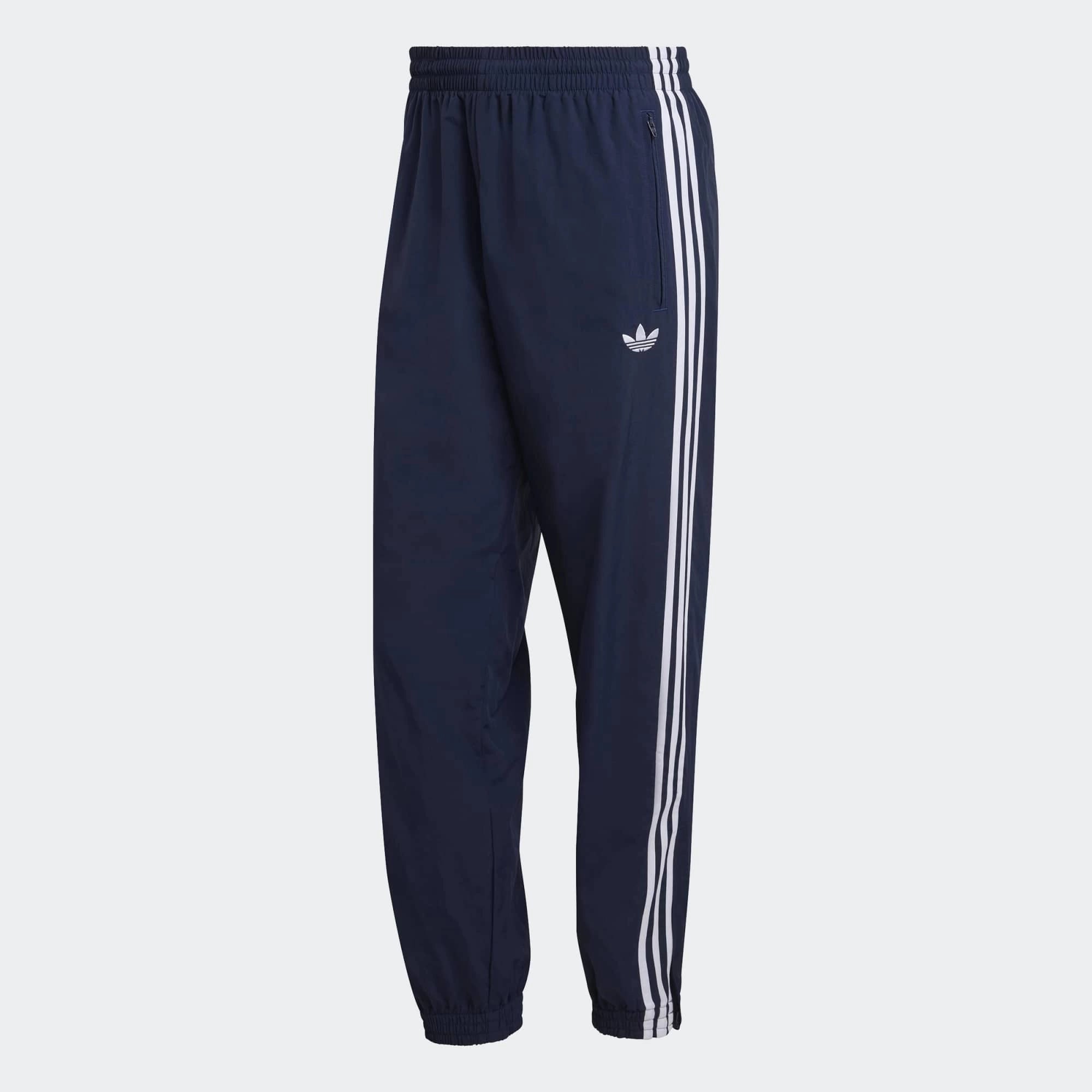 “Die adidas Originals Firebird Woven Trainingshose in Night Indigo (Dunkelblau) mit weißen 3-Streifen und leichtes, strapazierfähiges Webmaterial (Woven) bei Stickabush“.