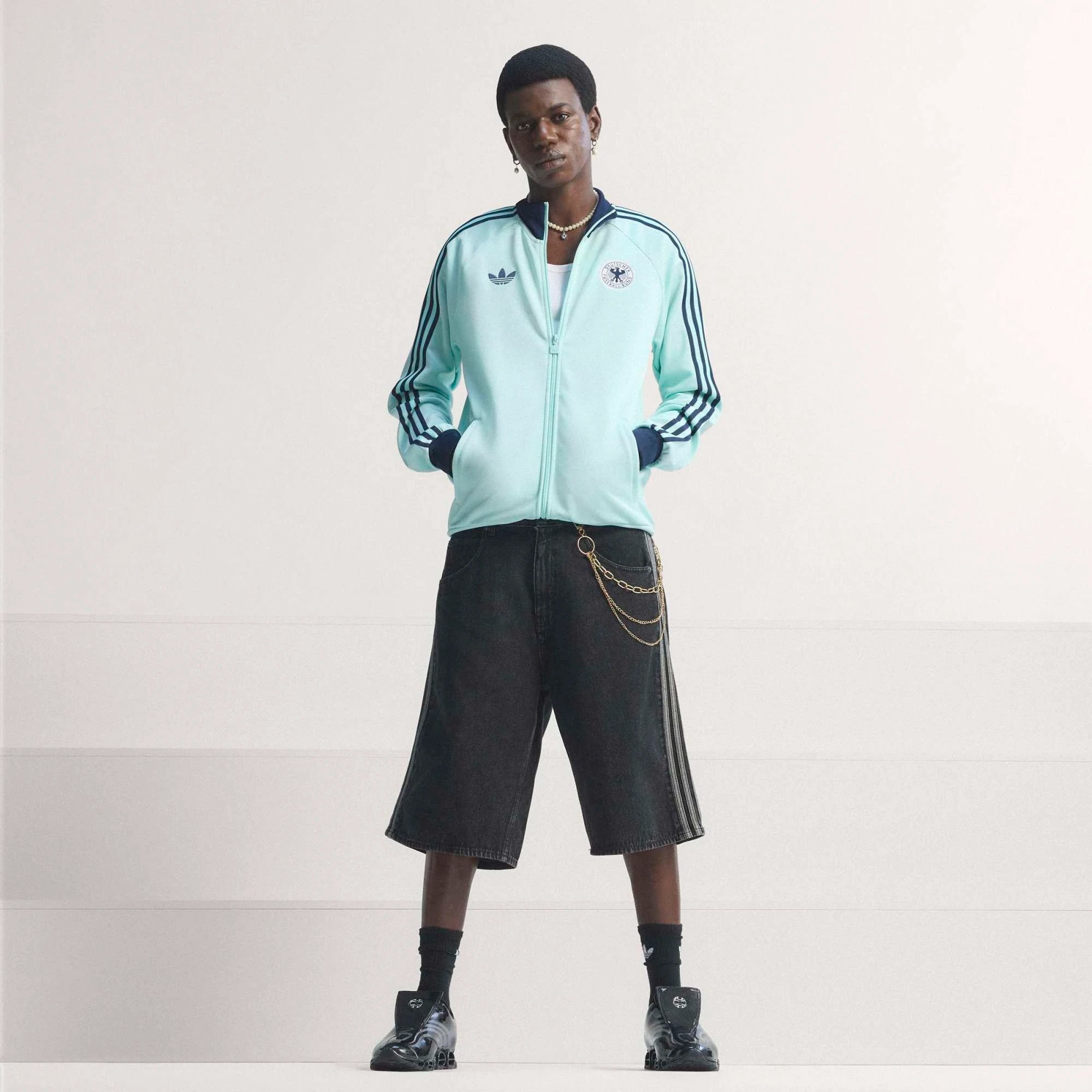 “Die türkise adidas Originals Deutschland OG Trainingsjacke (Semi Flash Aqua) mit klassischen weißen 3-Streifen und Retro-Details bei Stickabush“.