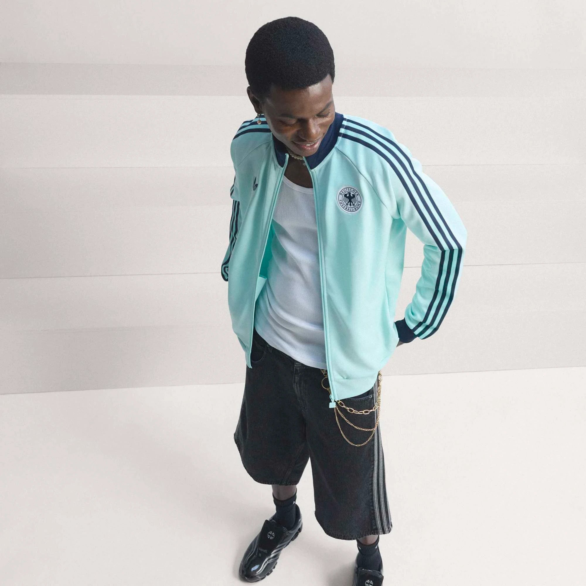 “Die türkise adidas Originals Deutschland OG Trainingsjacke (Semi Flash Aqua) mit klassischen weißen 3-Streifen und Retro-Details bei Stickabush“.