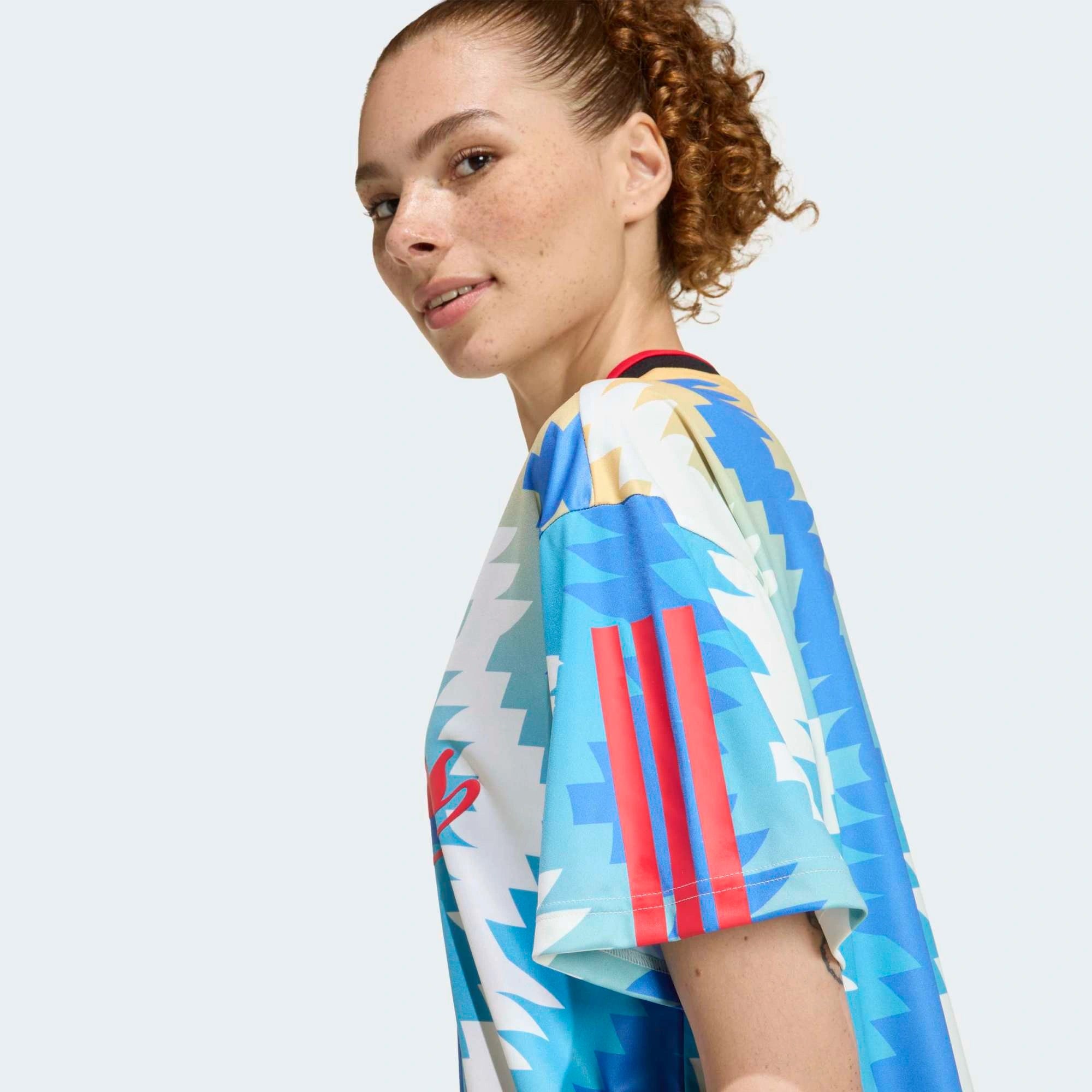 “Cremeweißes (Off White) adidas Originals Tiro x Common Goal Damen Trikot mit blauen Details und dezentem Allover-Print bei Stickabush.“