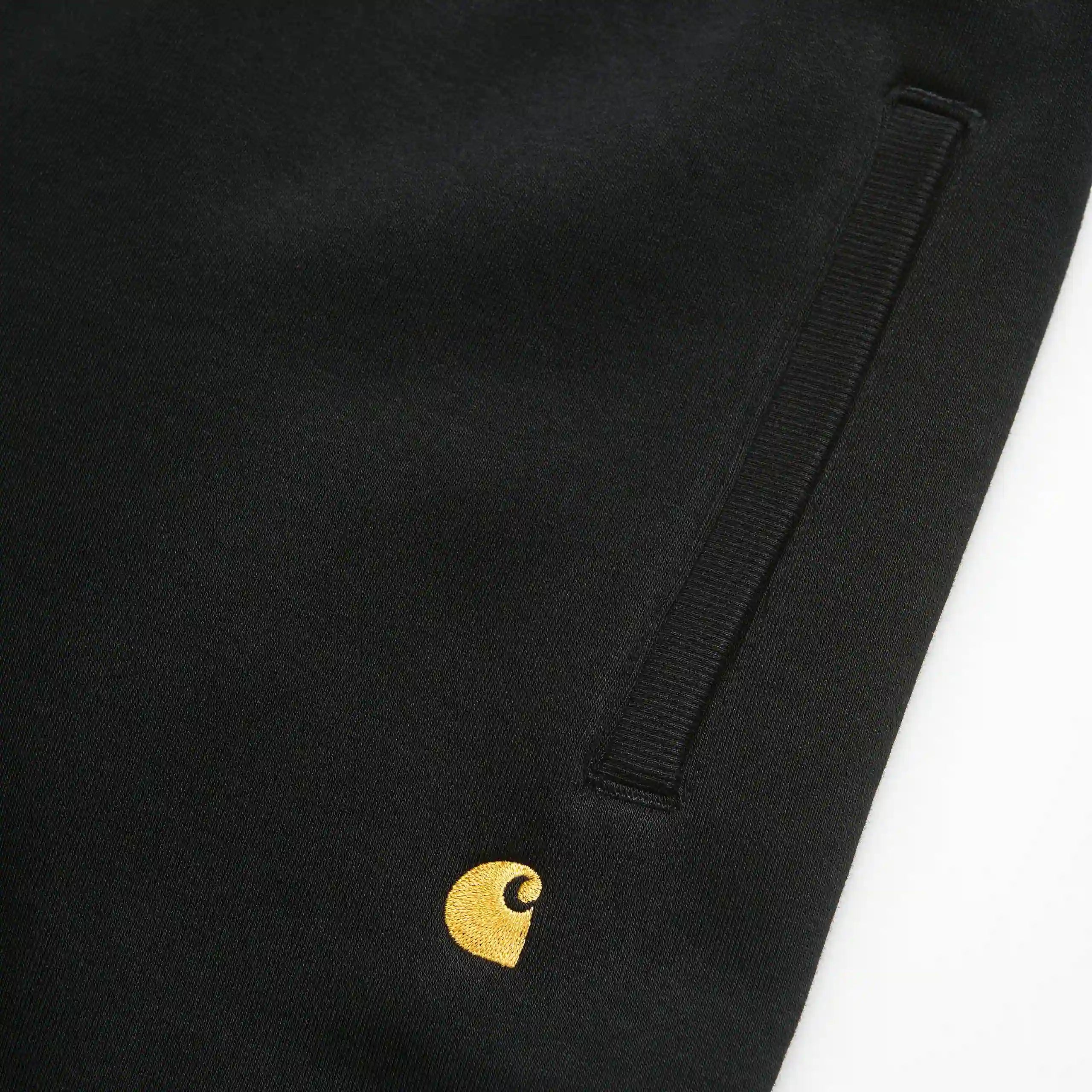 “Carhartt WIP Chase Sweat Pant in Black / Gold, eine Jogginghose aus weichem Baumwollmix, mit elastischem Bund und goldener Logo-Stickerei am Bein.“