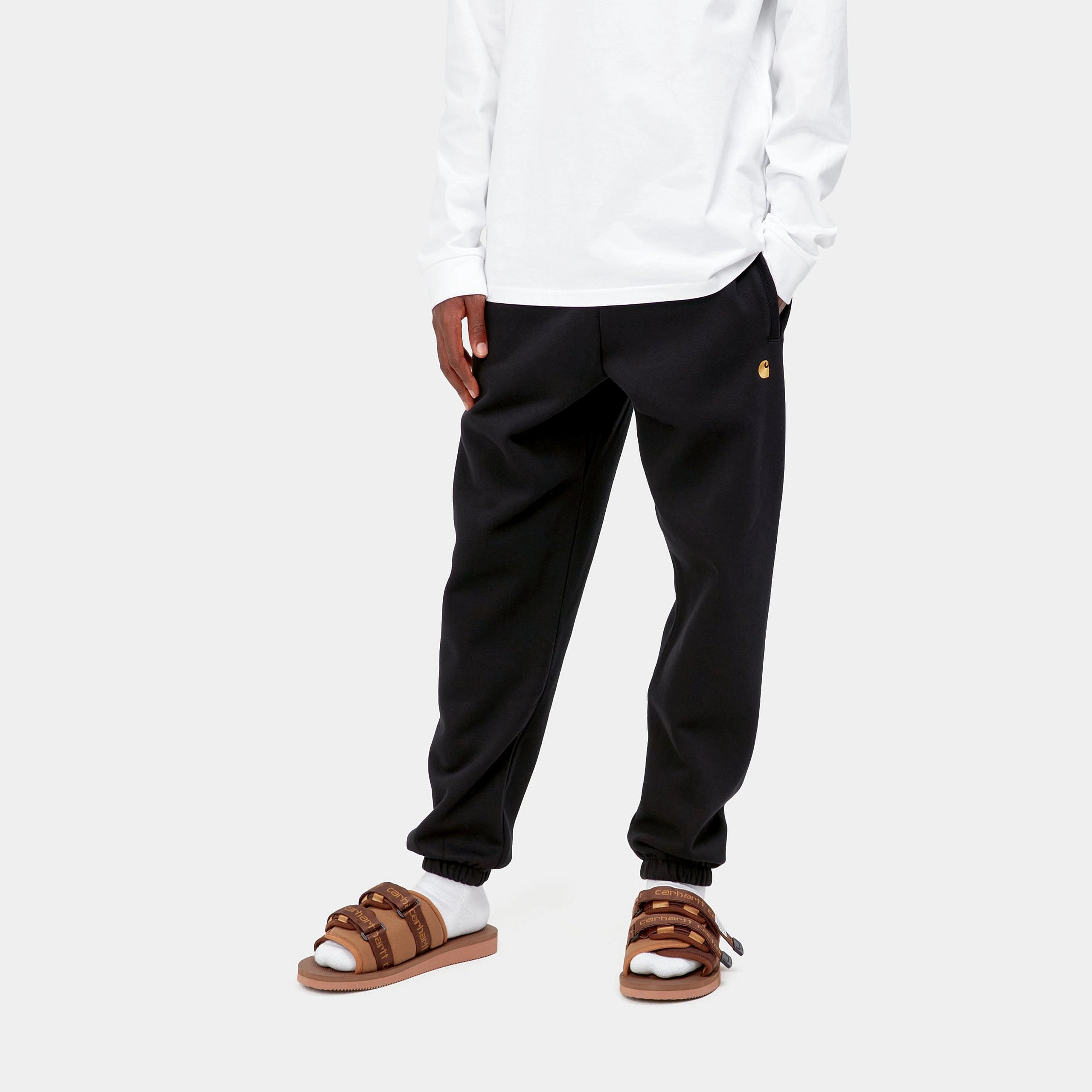“Carhartt WIP Chase Sweat Pant in Black / Gold, eine Jogginghose aus weichem Baumwollmix, mit elastischem Bund und goldener Logo-Stickerei am Bein.“