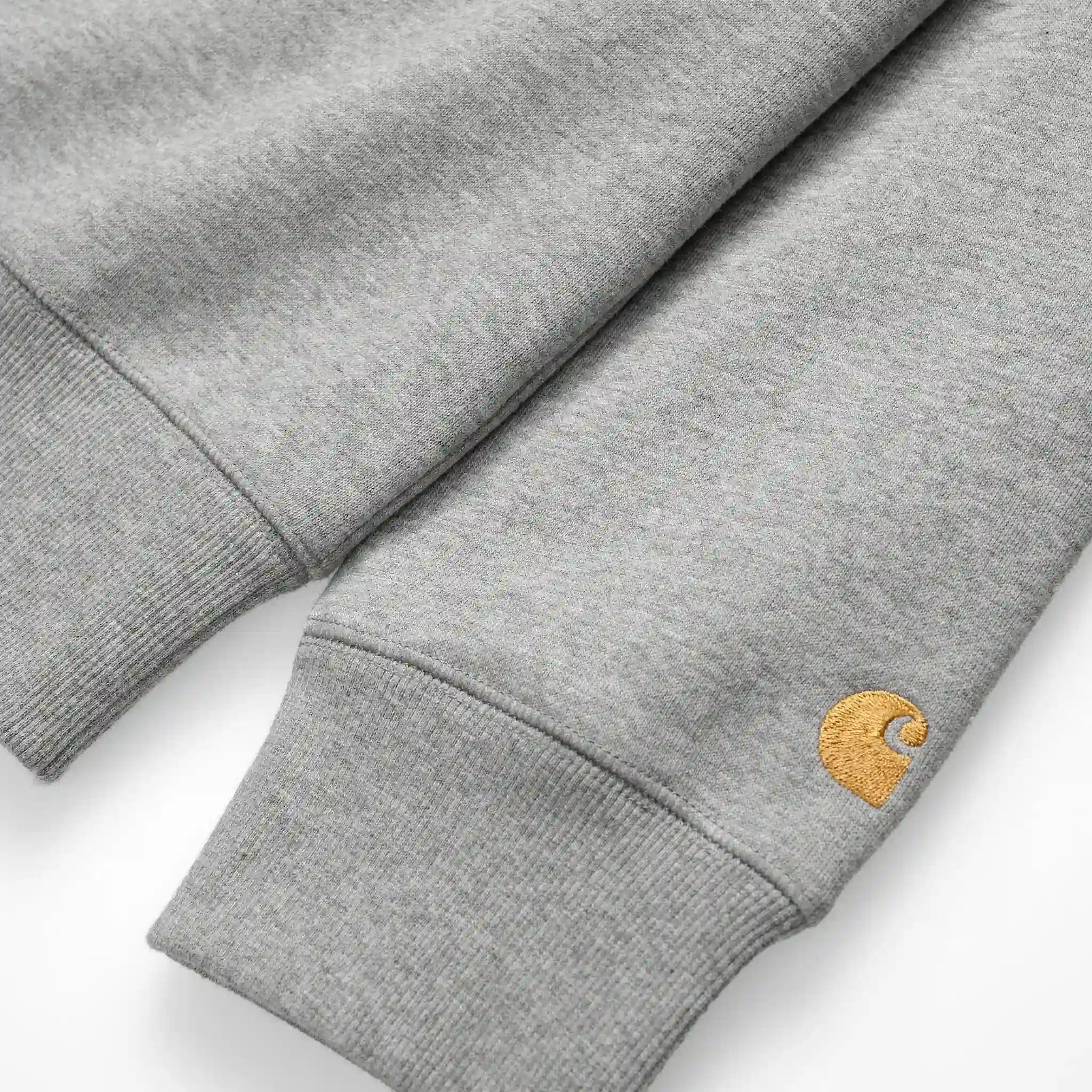 “Graumeliertes Carhartt WIP Chase Sweatshirt mit kleinem, goldenem "C"-Logo auf dem linken Ärmel. Klassischer Schnitt, Rundhalsausschnitt, gerippte Bündchen und Saum. Weicher Baumwollmix.“