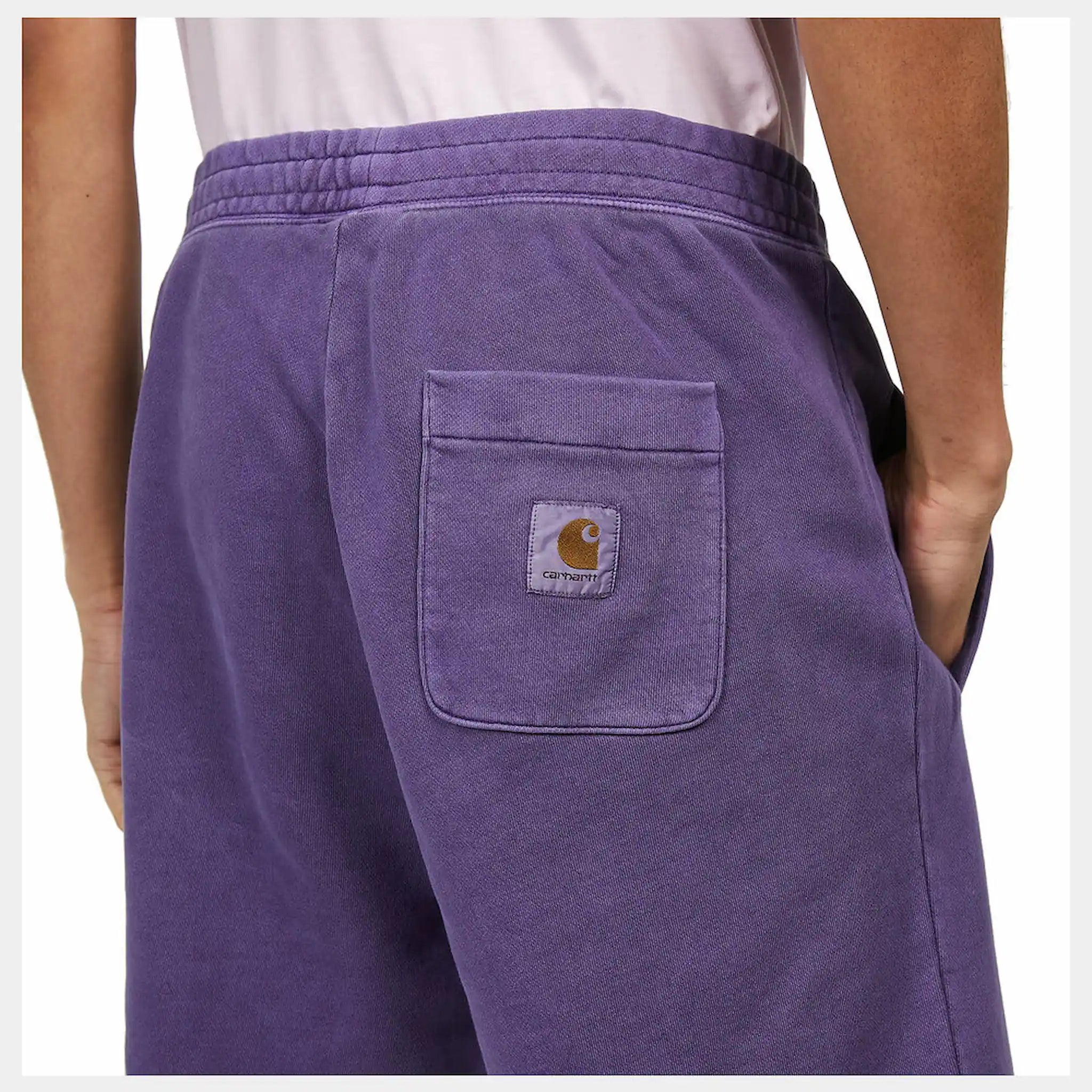 “Helles Lila ("Razzmic") Carhartt WIP Nelson Sweat Shorts. Kurze Herren-Sweathose aus weichem, stückgefärbtem Baumwolljersey. Lockere Passform, elastischer Bund mit Kordelzug, zwei Seitentaschen und eine Gesäßtasche mit kleinem, gewebtem Logo-Etikett. Bequeme Freizeithose für warme Tage.“