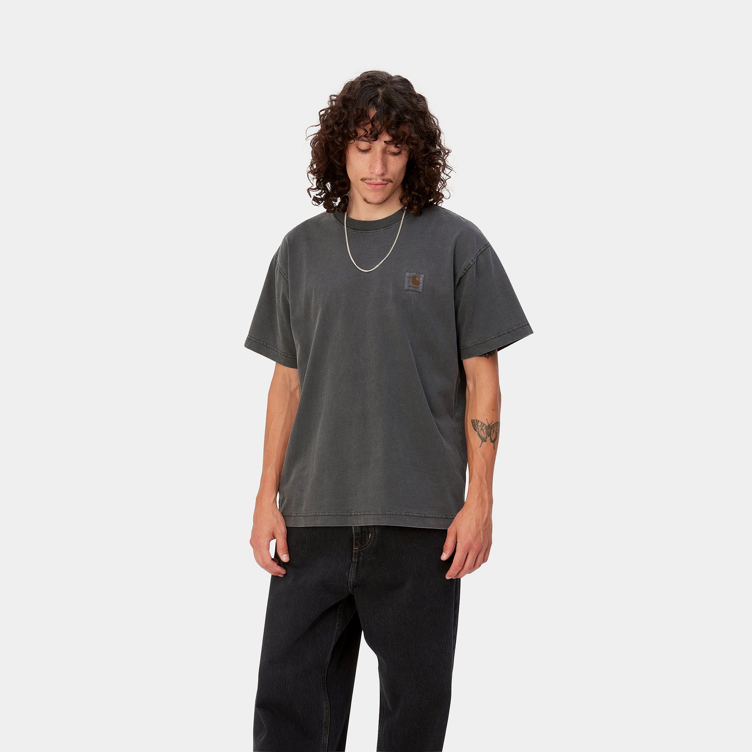 "Dunkelgraues ("Charcoal") Carhartt WIP S/S Nelson T-Shirt. Kurzärmliges Herren-T-Shirt aus weichem, stückgefärbtem Baumwolljersey. Bequeme, lockere Passform mit geripptem Rundhalsausschnitt und dezentem, gewebtem Carhartt Square Label auf der Brust. Alltagstaugliches Basic mit angenehmer Haptik."