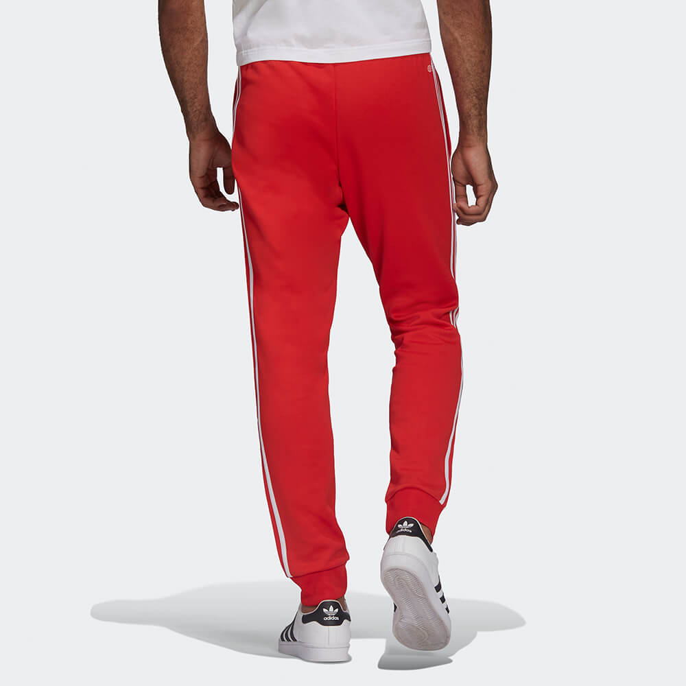 "Rote adidas Classics SST Track Pant mit weißen 3-Streifen und Trefoil-Logo, schmal zulaufendes Bein mit Rippbündchen bei Stickabush Berlin."