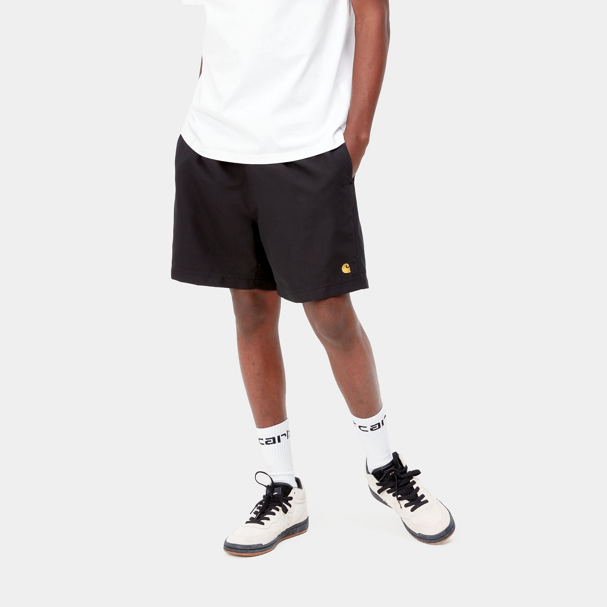 "Carhartt Chase Swim Trunk in Schwarz/Gold, Polyester, Badehose mit Kordelzug, goldene Logo-Stickerei."