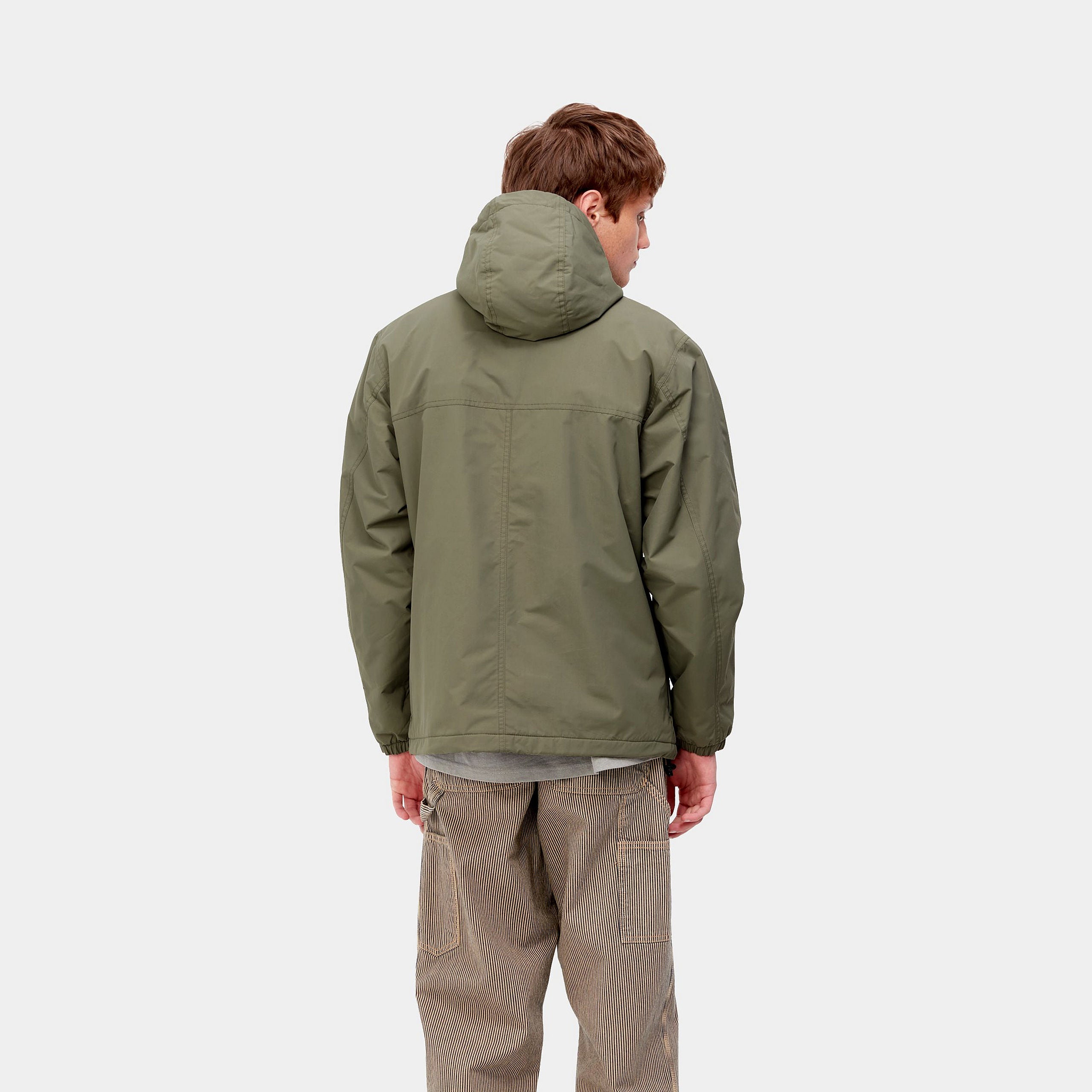 Carhartt WIP Windbreaker Pullover (Winter) – Seaweed / Black. Grüner Winter-Windbreaker aus Nylon mit Fleece-Futter, Kapuze, halbem Reißverschluss und schwarzer Logostickerei.