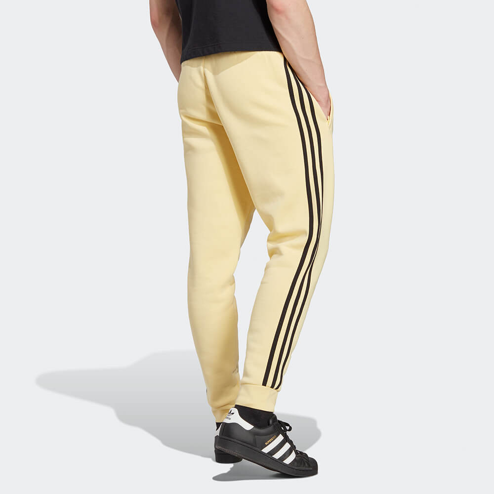 “Adidas Classics 3-Stripes Jogger – Yellow / Black. Gelbe Trainingshose aus weichem Stoff, mit schwarzen 3-Streifen und gesticktem Logo bei Stickabush Berlin."