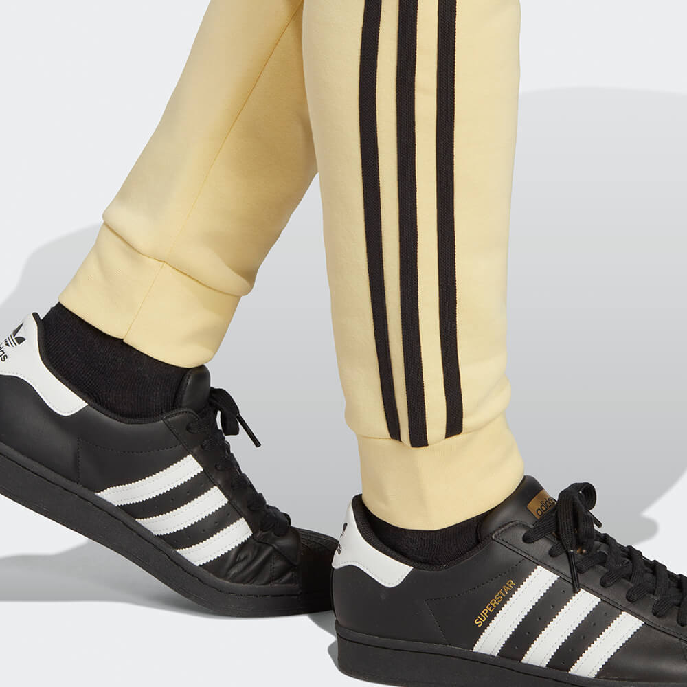 “Adidas Classics 3-Stripes Jogger – Yellow / Black. Gelbe Trainingshose aus weichem Stoff, mit schwarzen 3-Streifen und gesticktem Logo bei Stickabush Berlin."