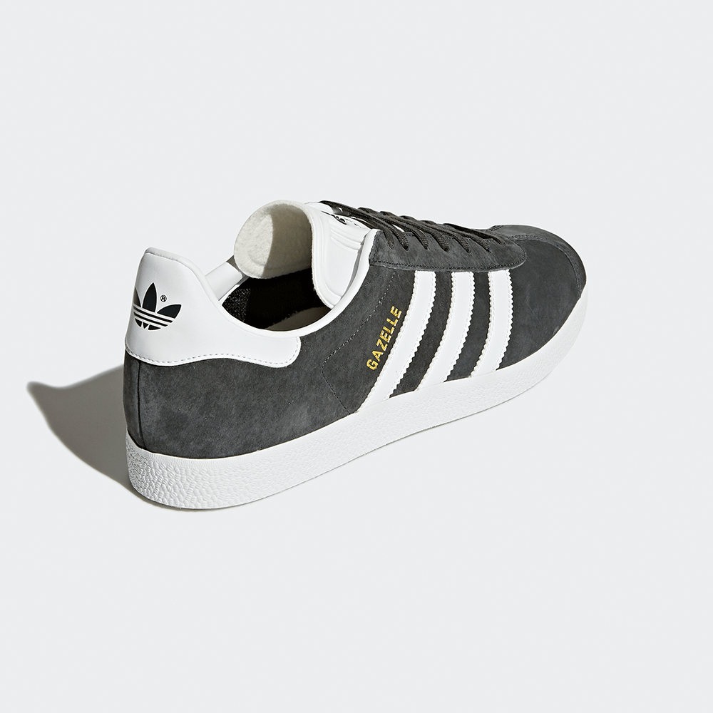 "Adidas Gazelle, Grau/Weiß, Wildleder, klassischer Sneaker in Grau mit weißen Streifen und goldener 'Gazelle'-Aufschrift."