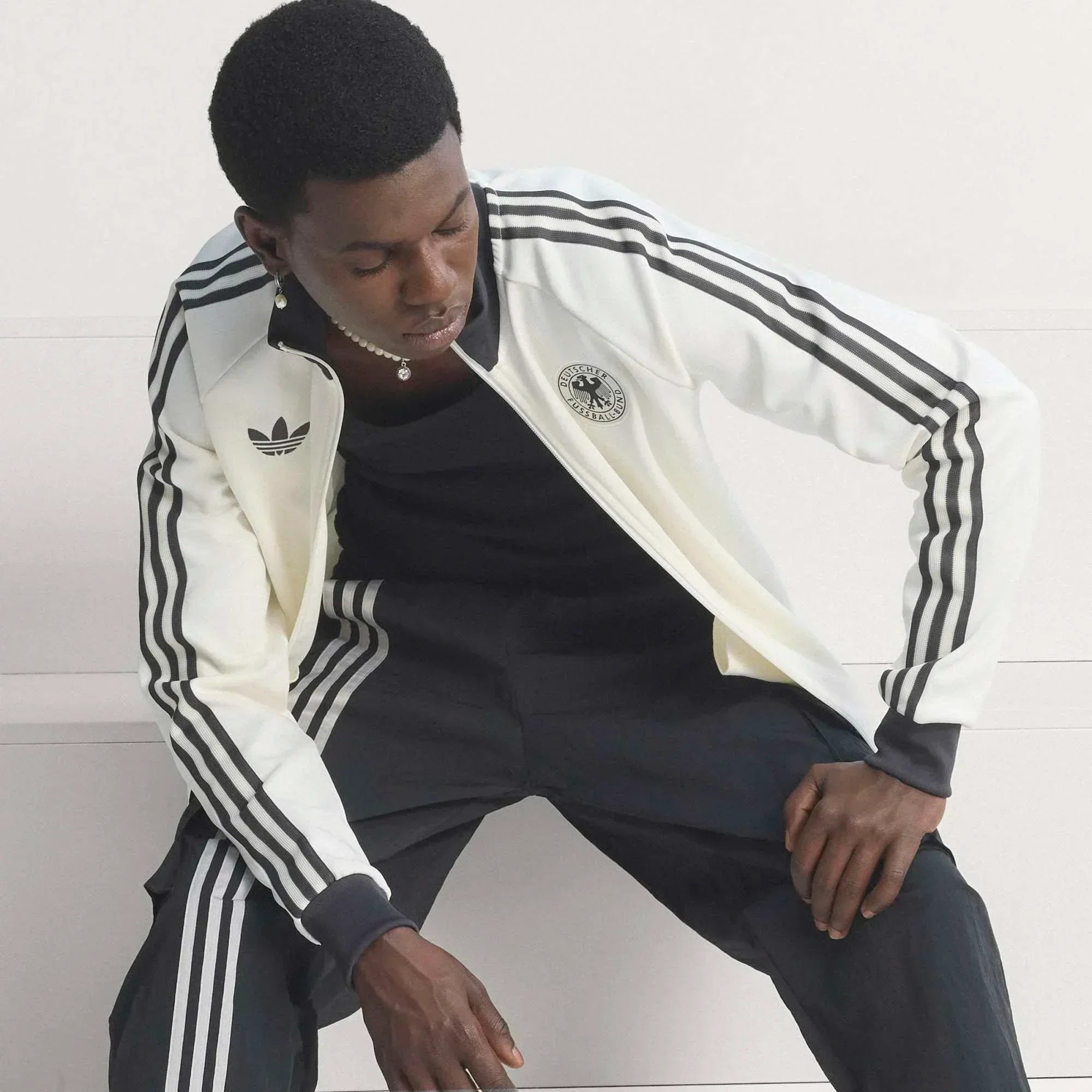 Model trägt im Berliner Studio die adidas DFB-Archive-Kollektion und Retro-Fußball-Trainingsanzug im Blokecore-Style.
