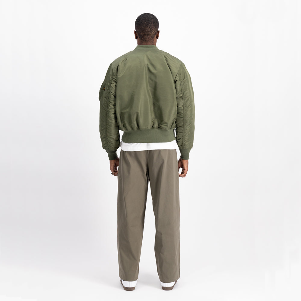 “Alpha Industries MA-1 (HERITAGE) Bomberjacke in Sage Green, aus robustem Nylon, mit orangefarbenem Innenfutter und ikonischem Ärmeltaschen-Design.“