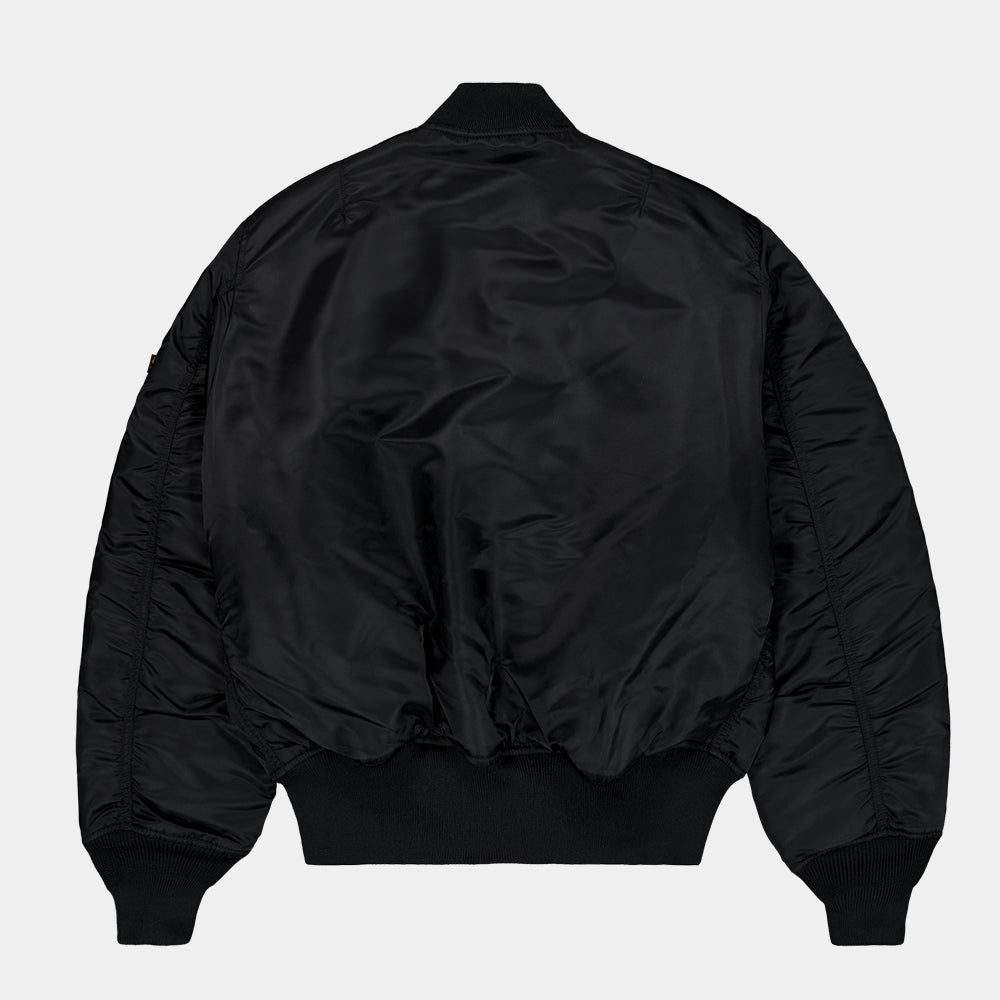“Alpha Industries MA-1 (HERITAGE) Bomberjacke in Schwarz, aus robustem Nylon, mit ikonischem Flight-Tag am Ärmel und gestepptem orangenem Innenfutter.“