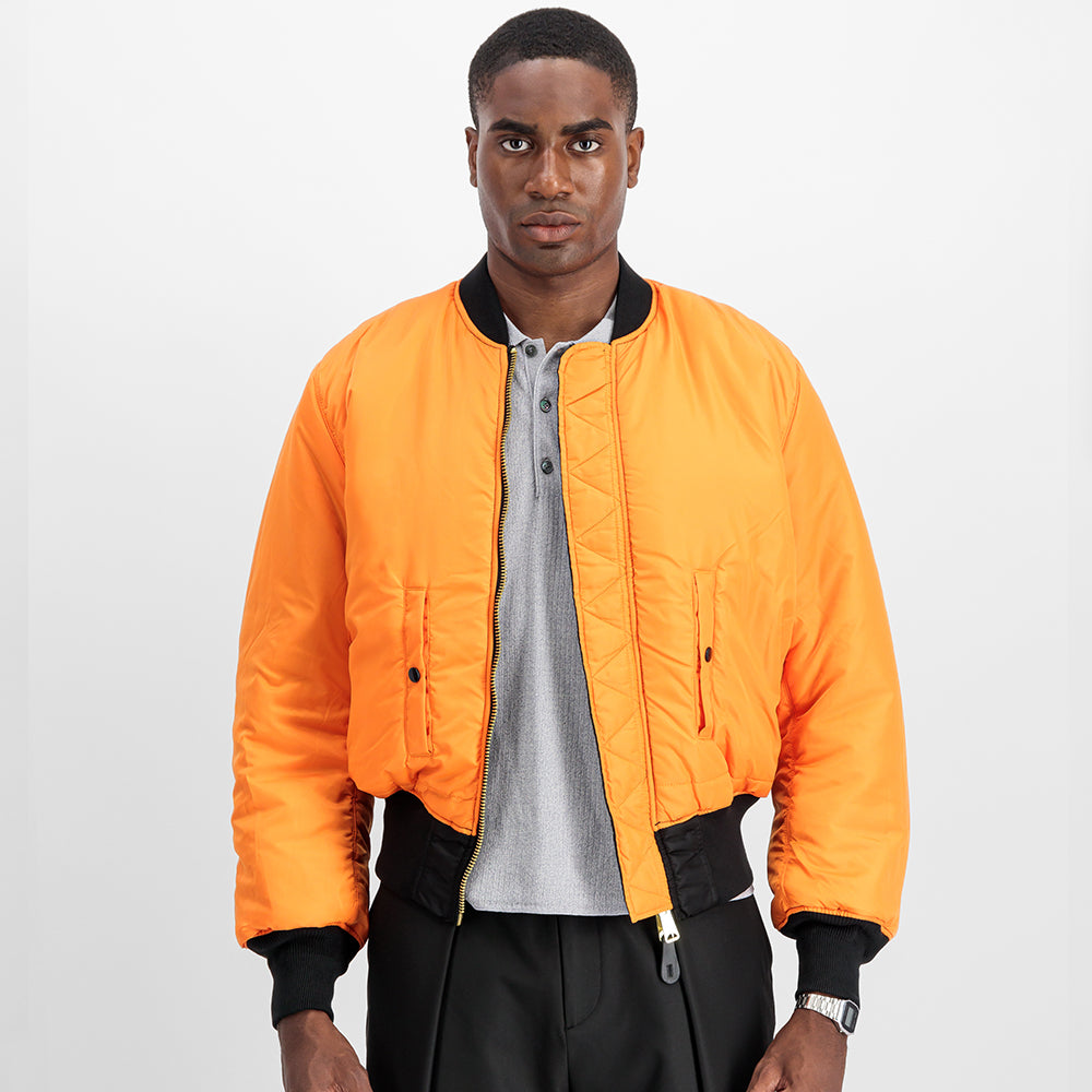 “Alpha Industries MA-1 (HERITAGE) Bomberjacke in Schwarz, aus robustem Nylon, mit ikonischem Flight-Tag am Ärmel und gestepptem orangenem Innenfutter.“