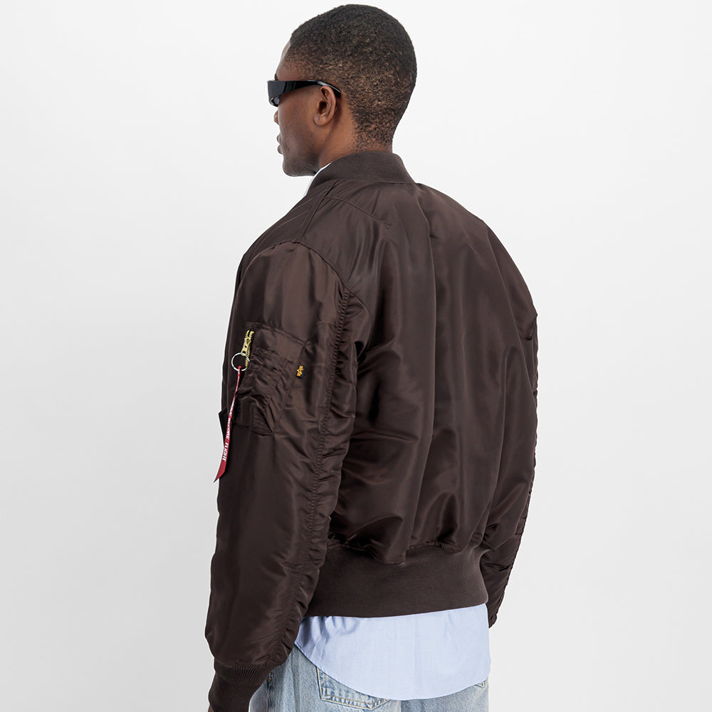 "Alpha Industries MA-1 (HERITAGE) Bomberjacke in Hunter Brown, aus strapazierfähigem Nylon, mit Rippbündchen und ikonischem Flight-Tag am Ärmel."