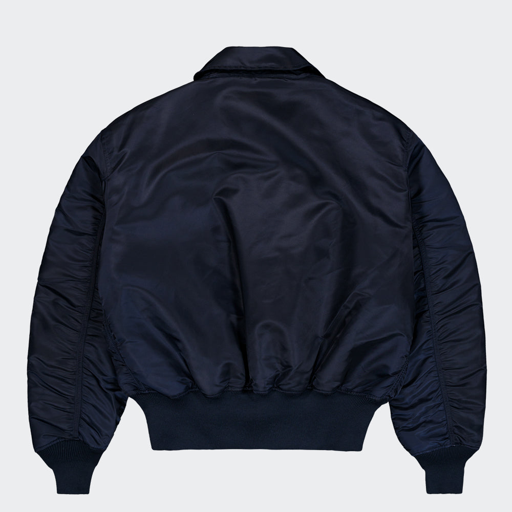 "Alpha Industries CWU 45 Heritage Bomberjacke in Rep. Blue, aus robustem Nylon, mit Rippbündchen, Utility-Tasche am Ärmel und gestepptem Innenfutter."