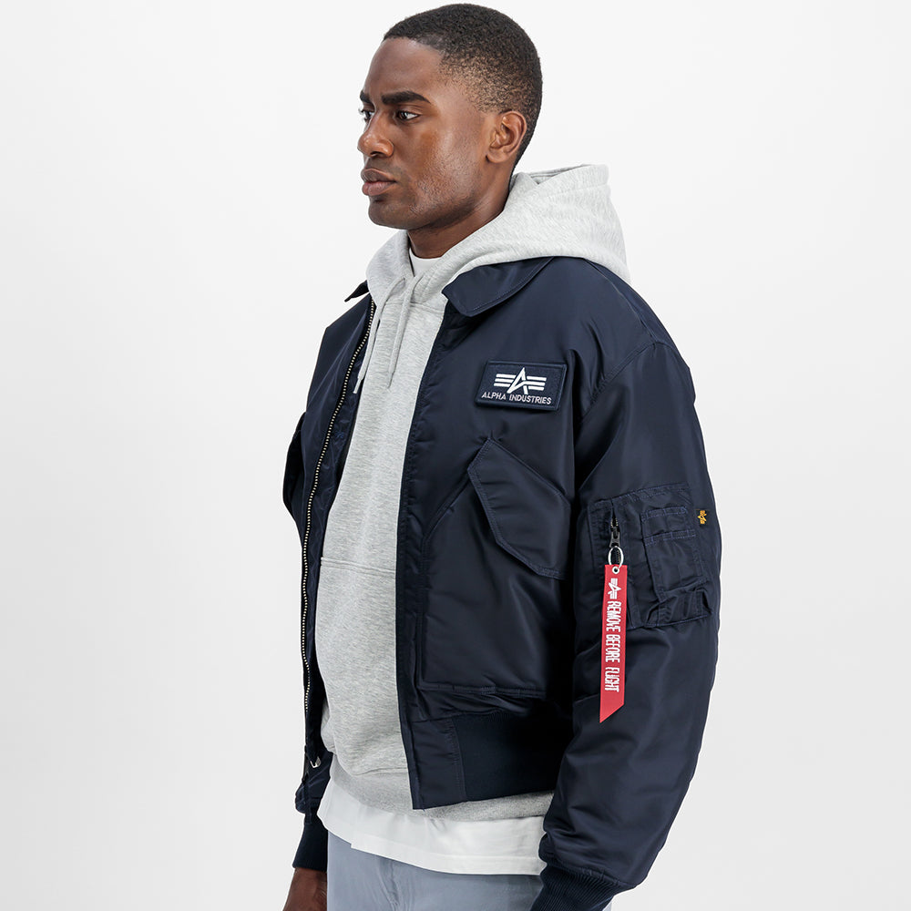 "Alpha Industries CWU 45 Heritage Bomberjacke in Rep. Blue, aus robustem Nylon, mit Rippbündchen, Utility-Tasche am Ärmel und gestepptem Innenfutter."