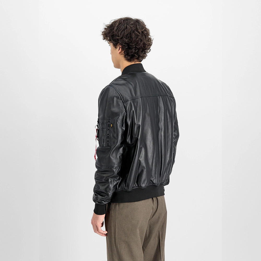 „Schwarze Alpha Industries MA-1 Lederjacke mit Strickkragen, Utility Pocket am Ärmel und rotem Remove Before Flight Tag vor neutralem Hintergrund bei Stickabush Berlin.“